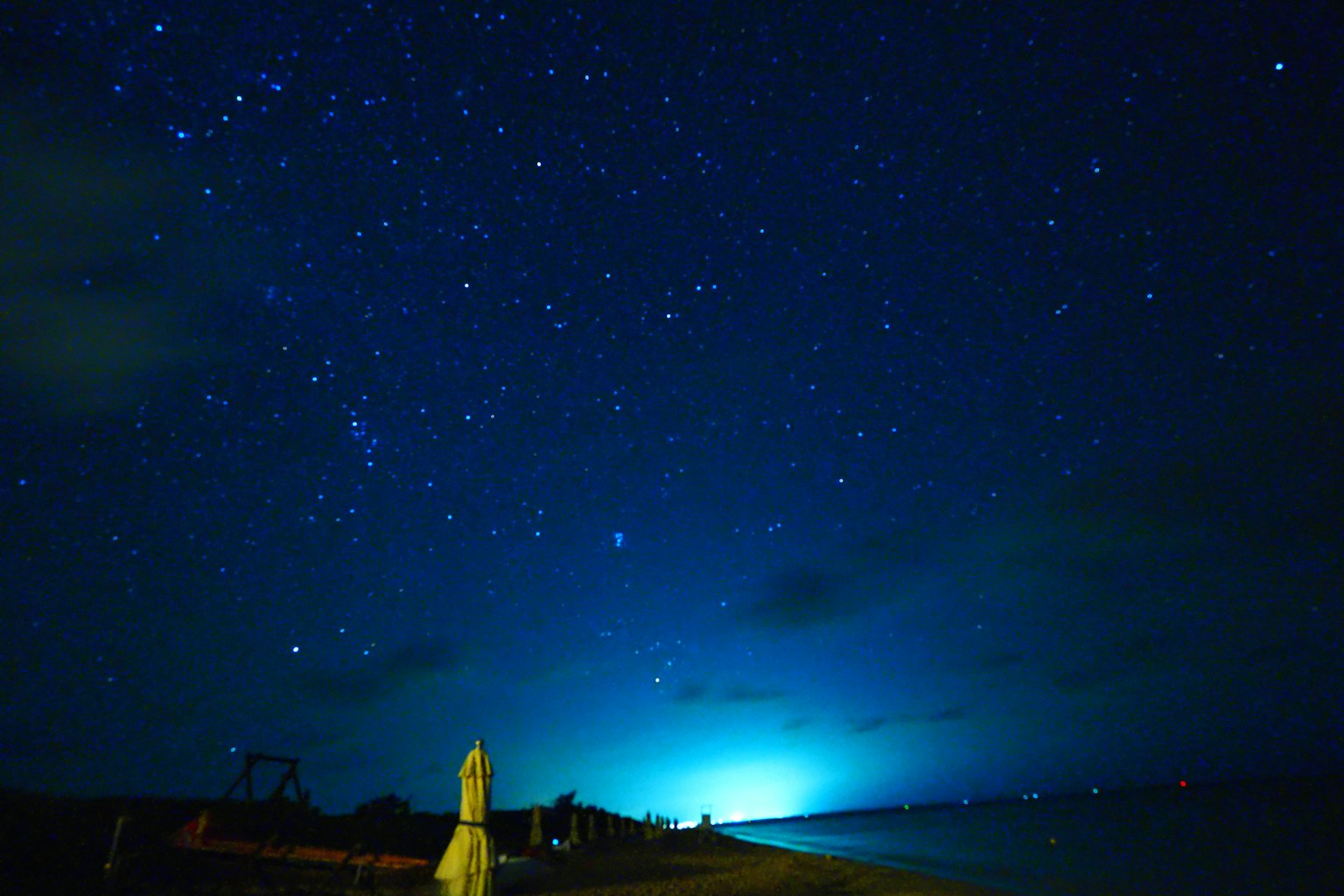 Langit berbintang dengan cahaya biru di pantai