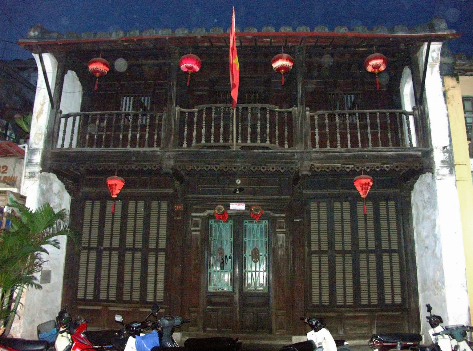 Rumah kayu tradisional dua lantai dengan lentera merah di malam hari