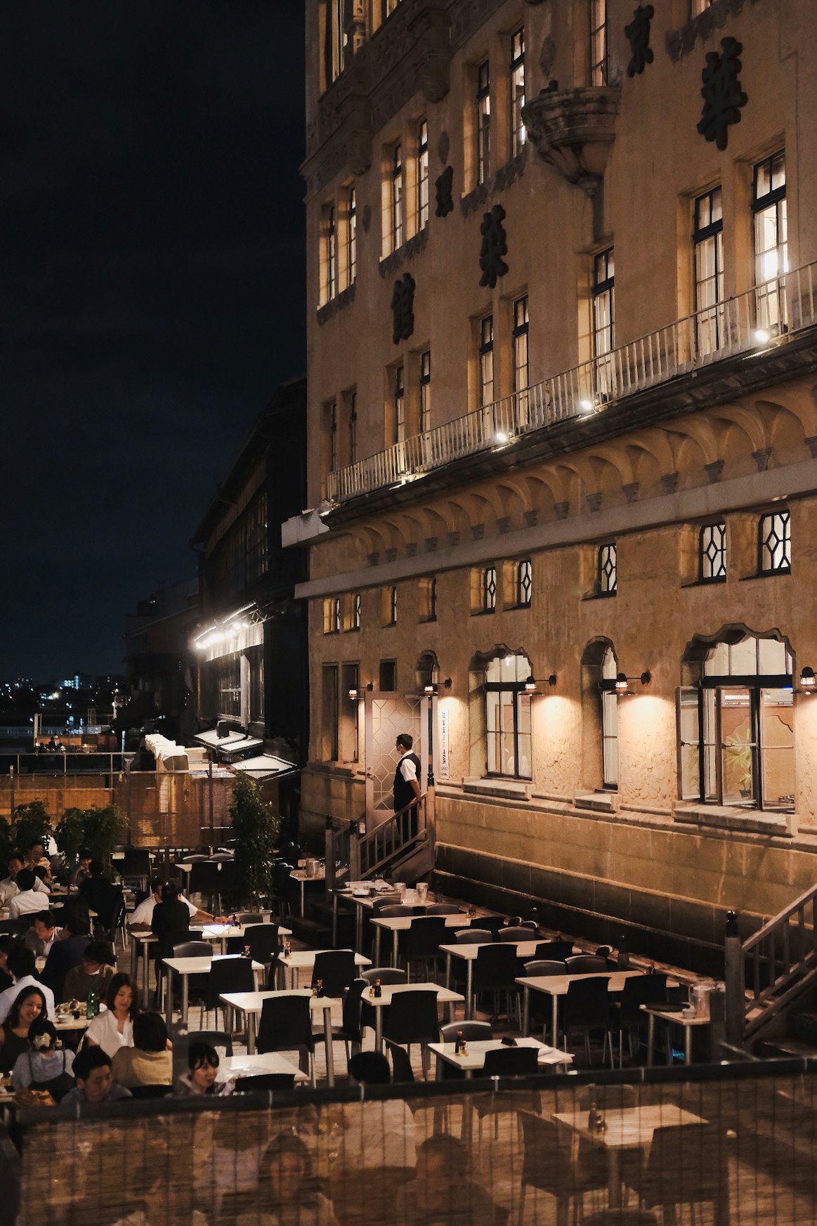 tables extérieures et lampadaires dans une ruelle de Kyoto la nuit
