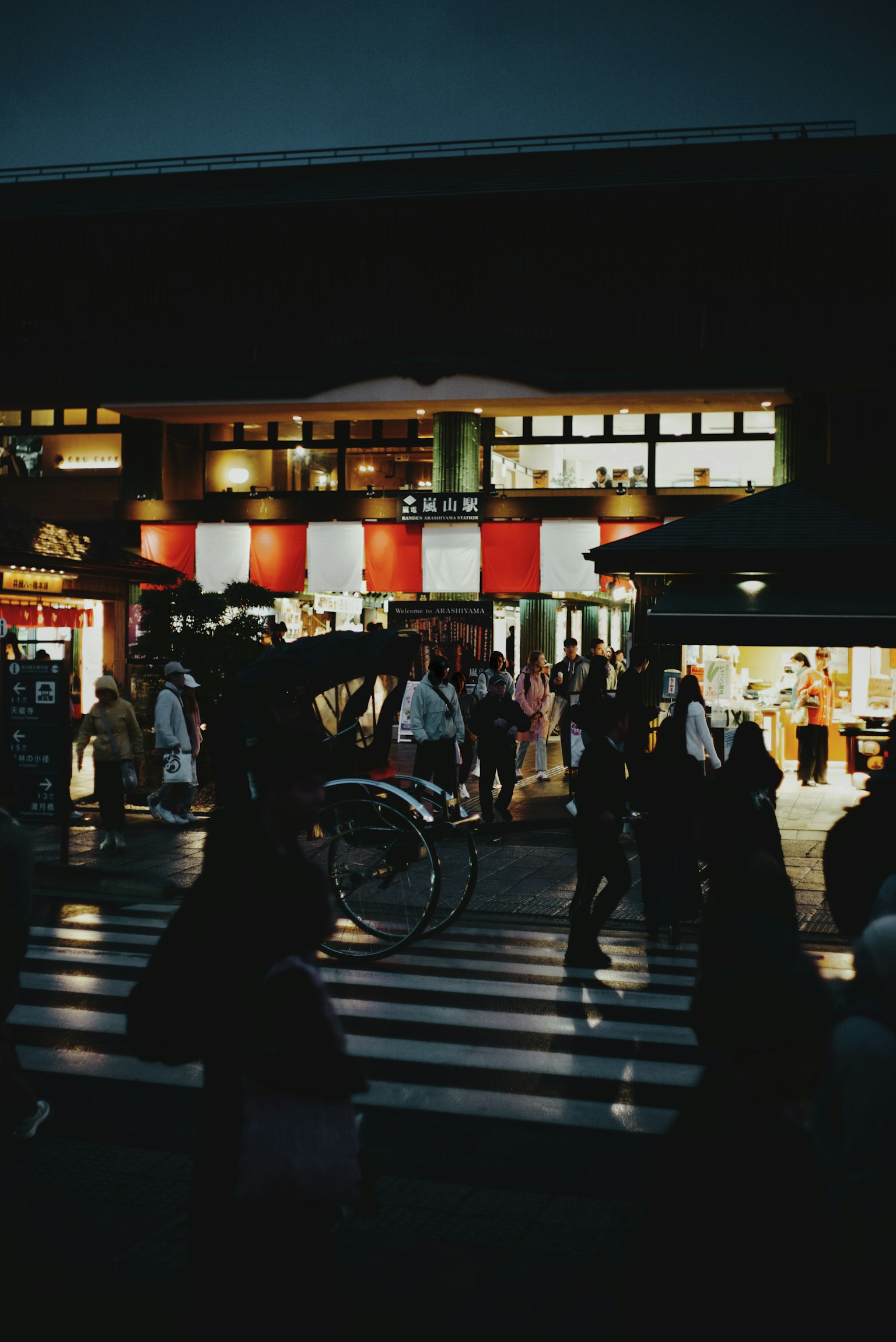Una scena di strada affollata di notte con pedoni e un risciò