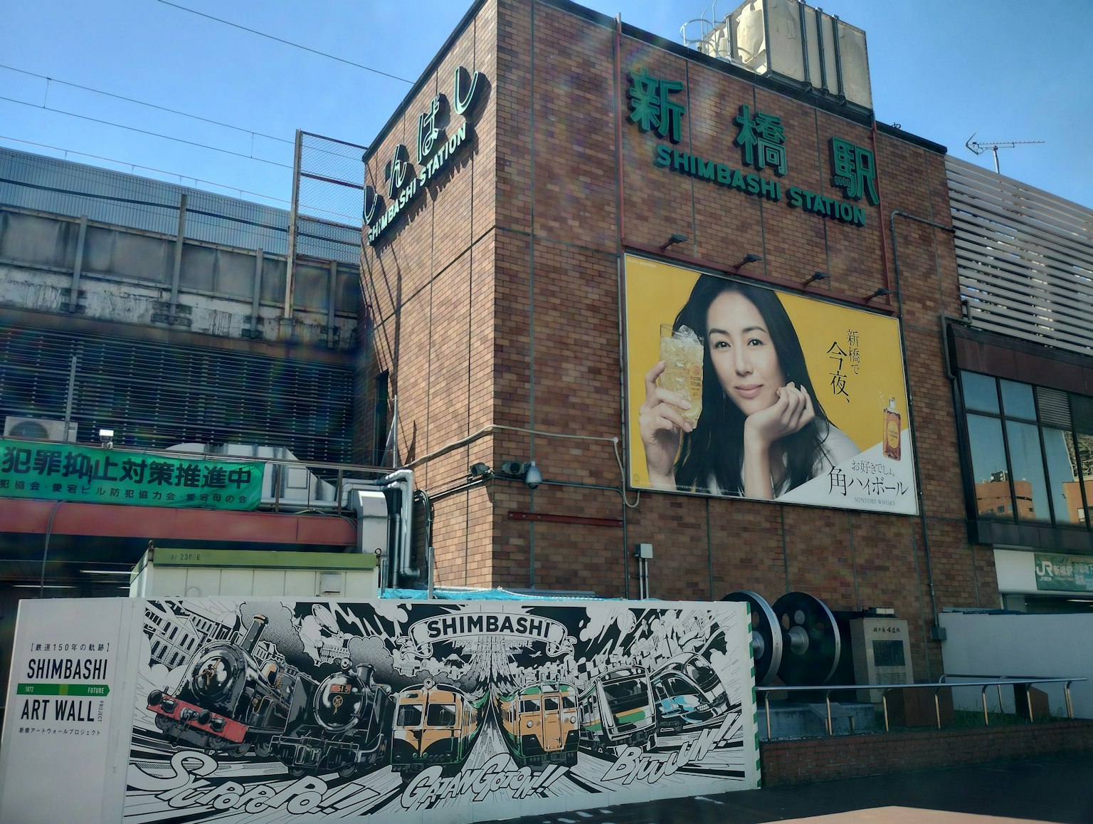 Edificio de ladrillo con gran anuncio y mural artístico