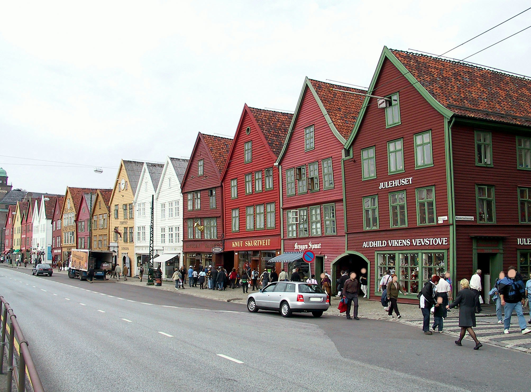 Bunte Holzfassaden in einer Einkaufsstraße mit Fußgängern