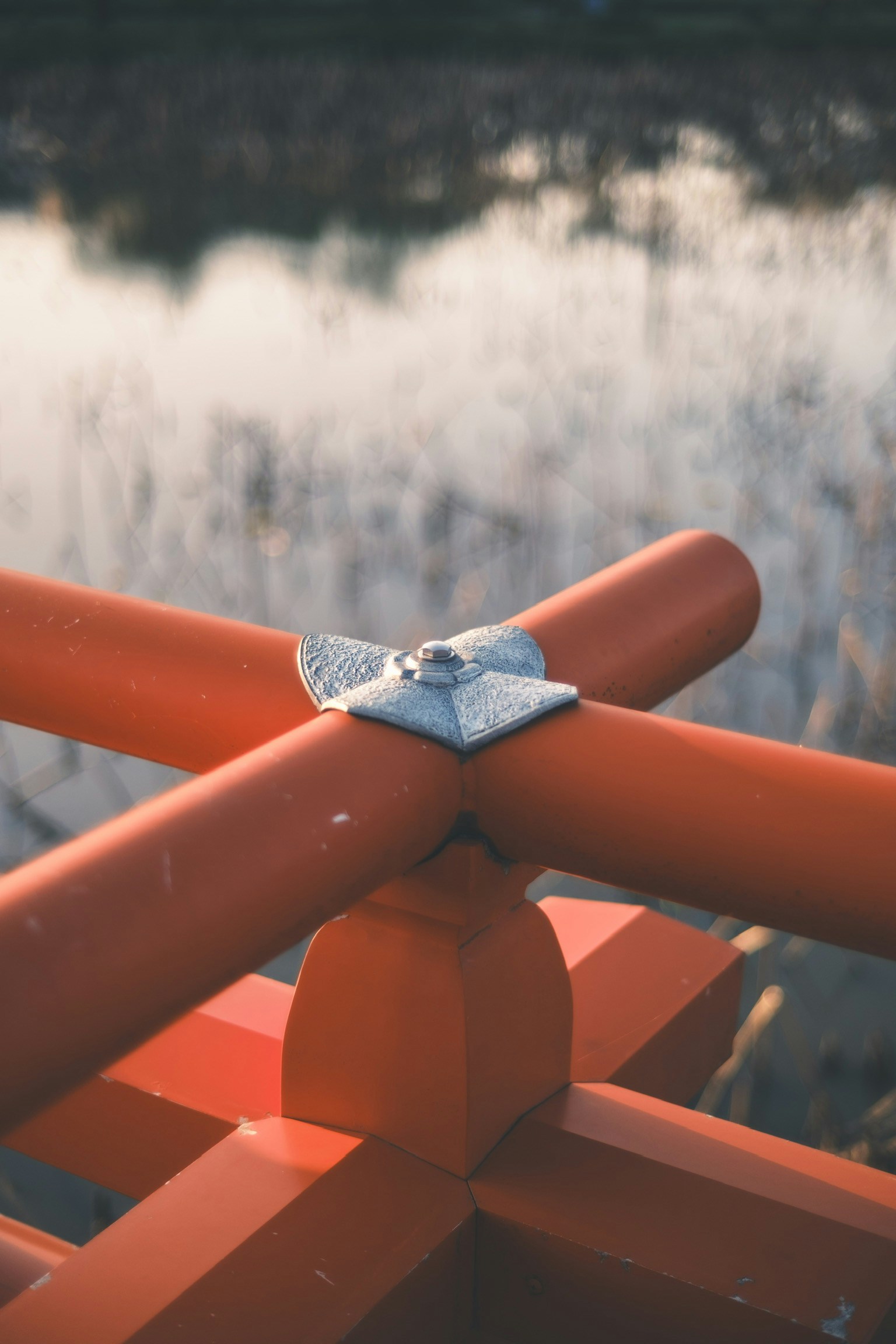 Intersection of red wooden railing with water reflection