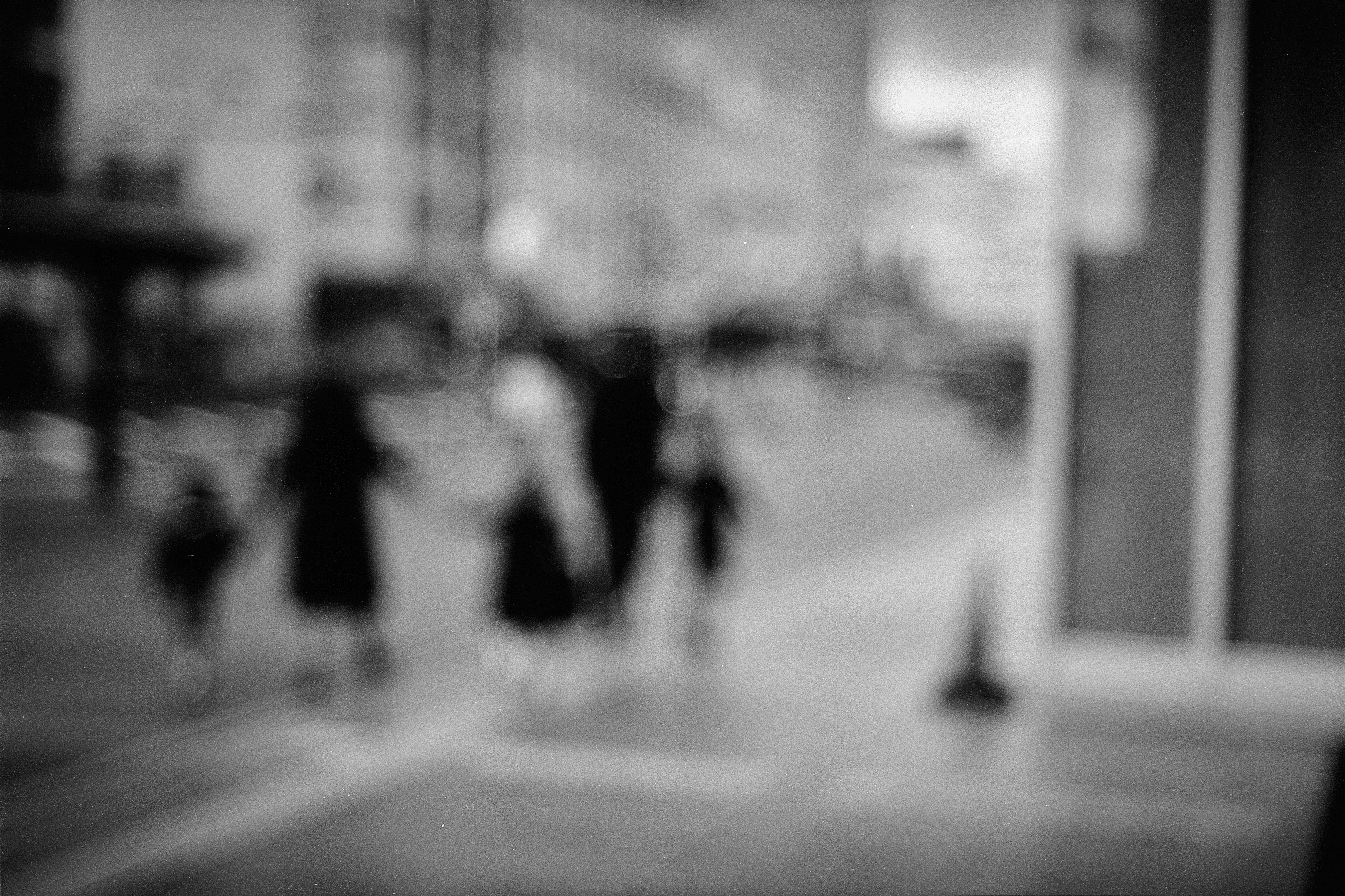 モノクロの街角を行き交う人々のぼけた通りの風景