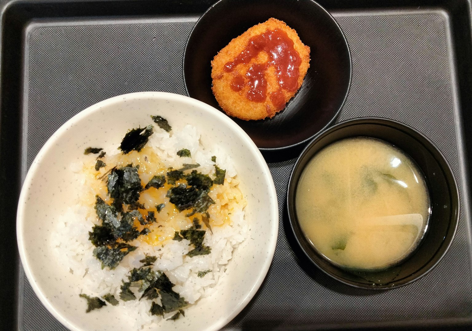 Japanisches Gericht mit Reis, garniert mit Algen, begleitet von Miso-Suppe und einer Beilage