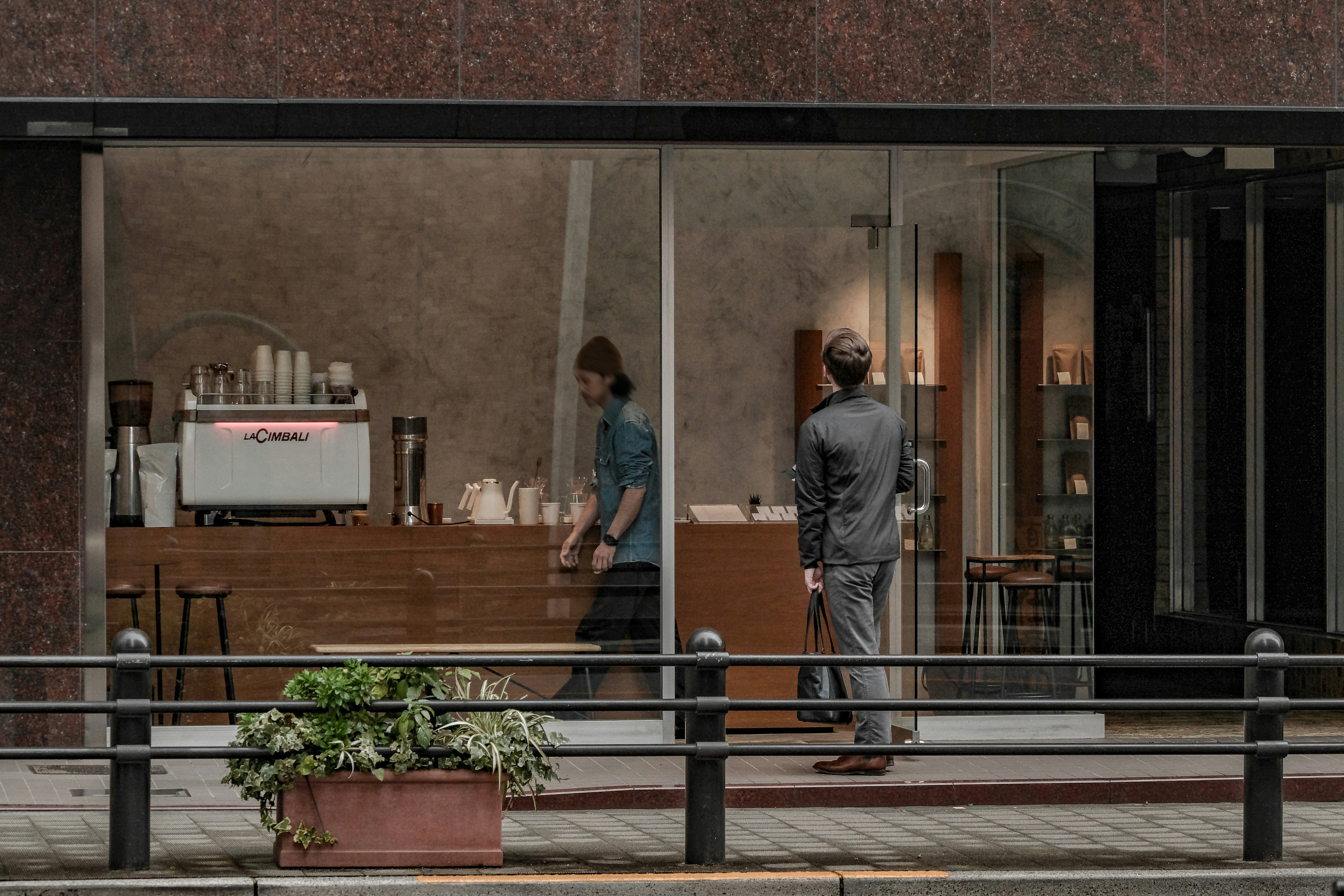 開店したてのカフェの店先で人が入る朝の街並み