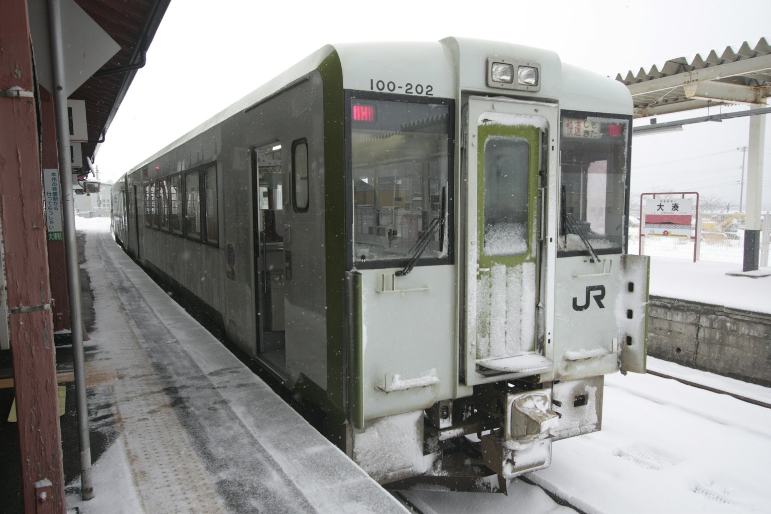 Green train stopped at a snowy station