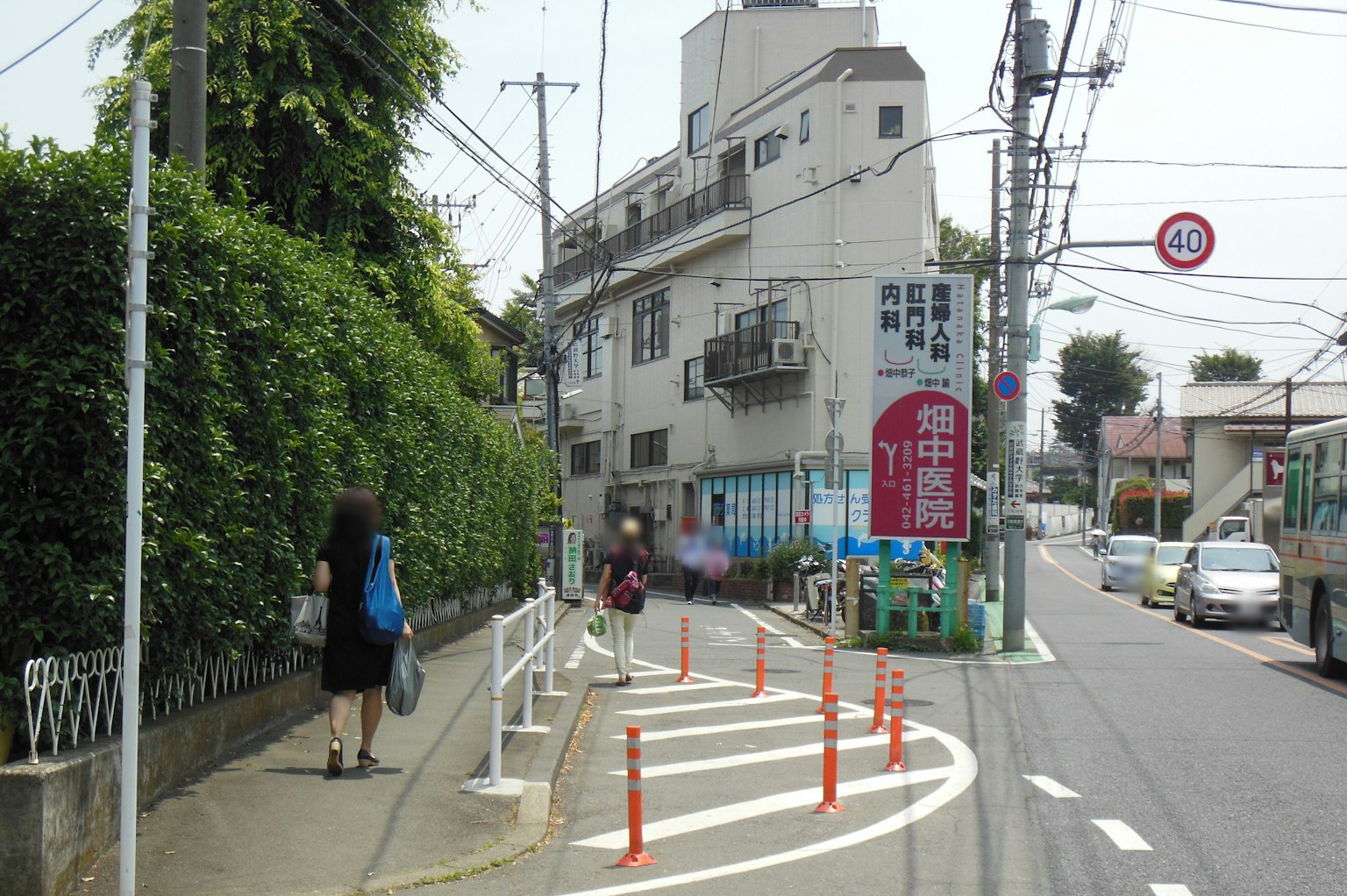 ทิวทัศน์ถนนที่อยู่อาศัยพร้อมรั้วสีเขียวและคนเดินถนน