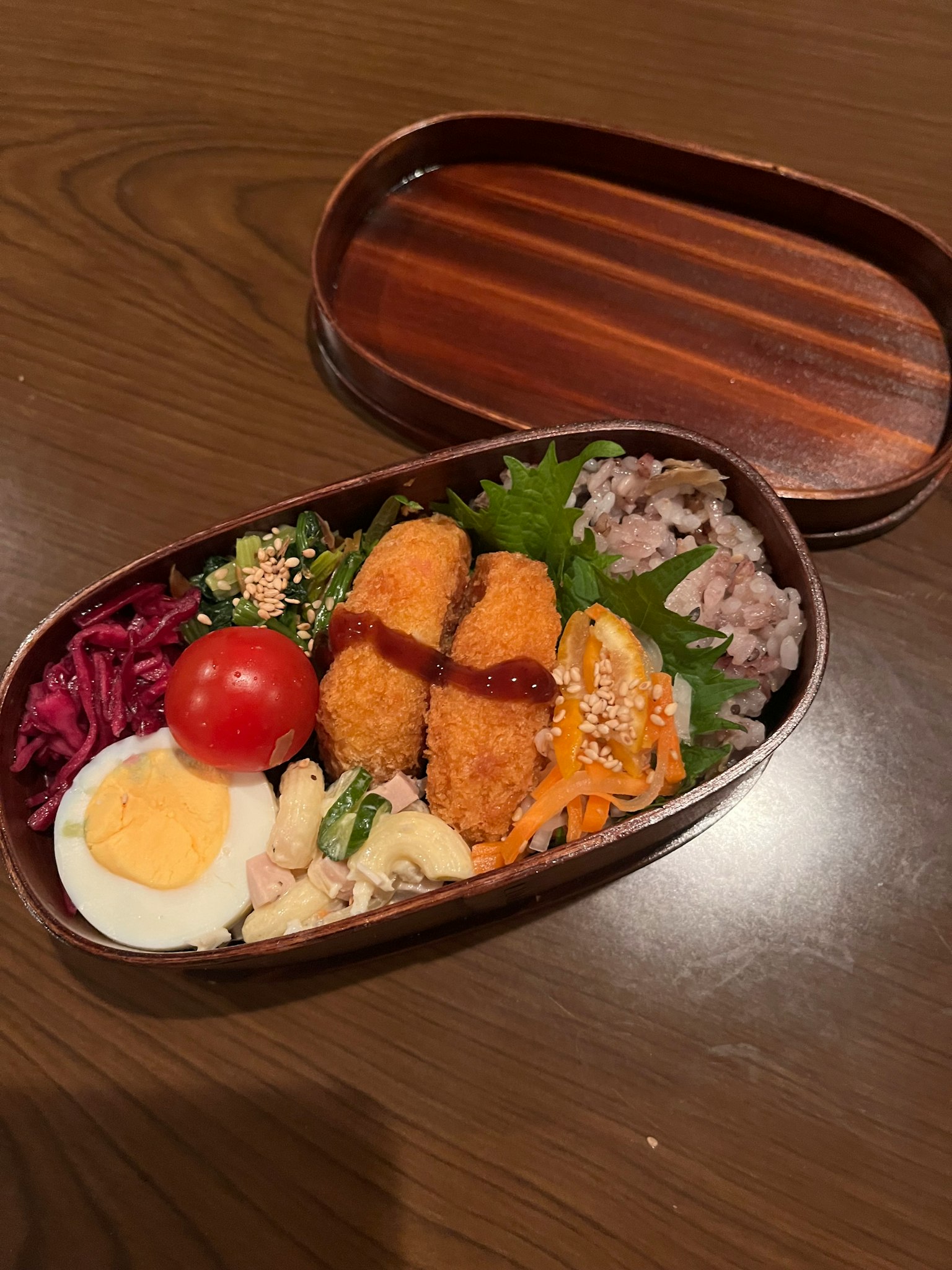 Hộp bento bằng gỗ đầy các món ăn khác nhau Salad nhiều màu và cơm Trứng luộc và cà chua bi bao gồm