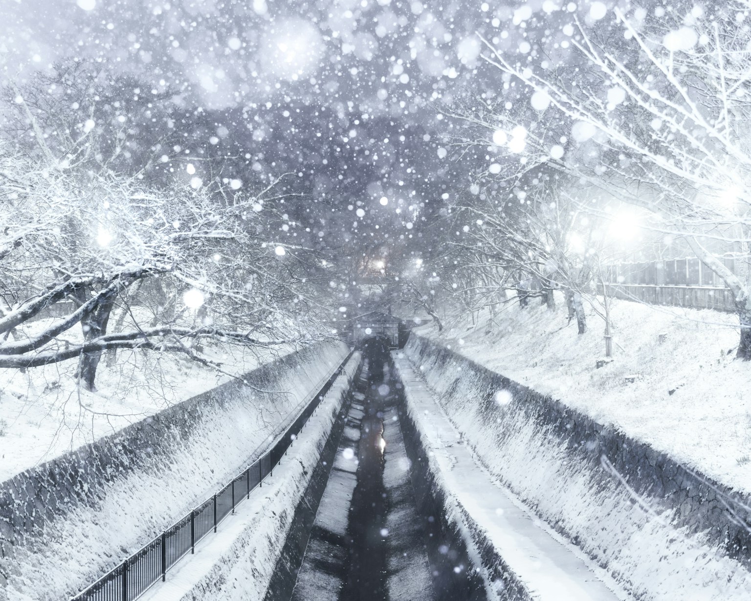 Schneebedeckte Landschaft mit fallendem Schnee und einem Fluss