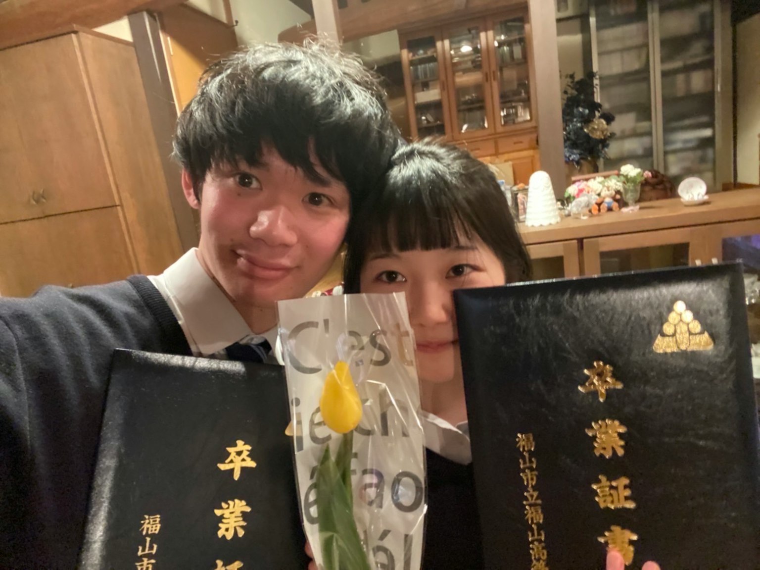 Deux étudiants souriants prenant un selfie avec des certificats de graduation