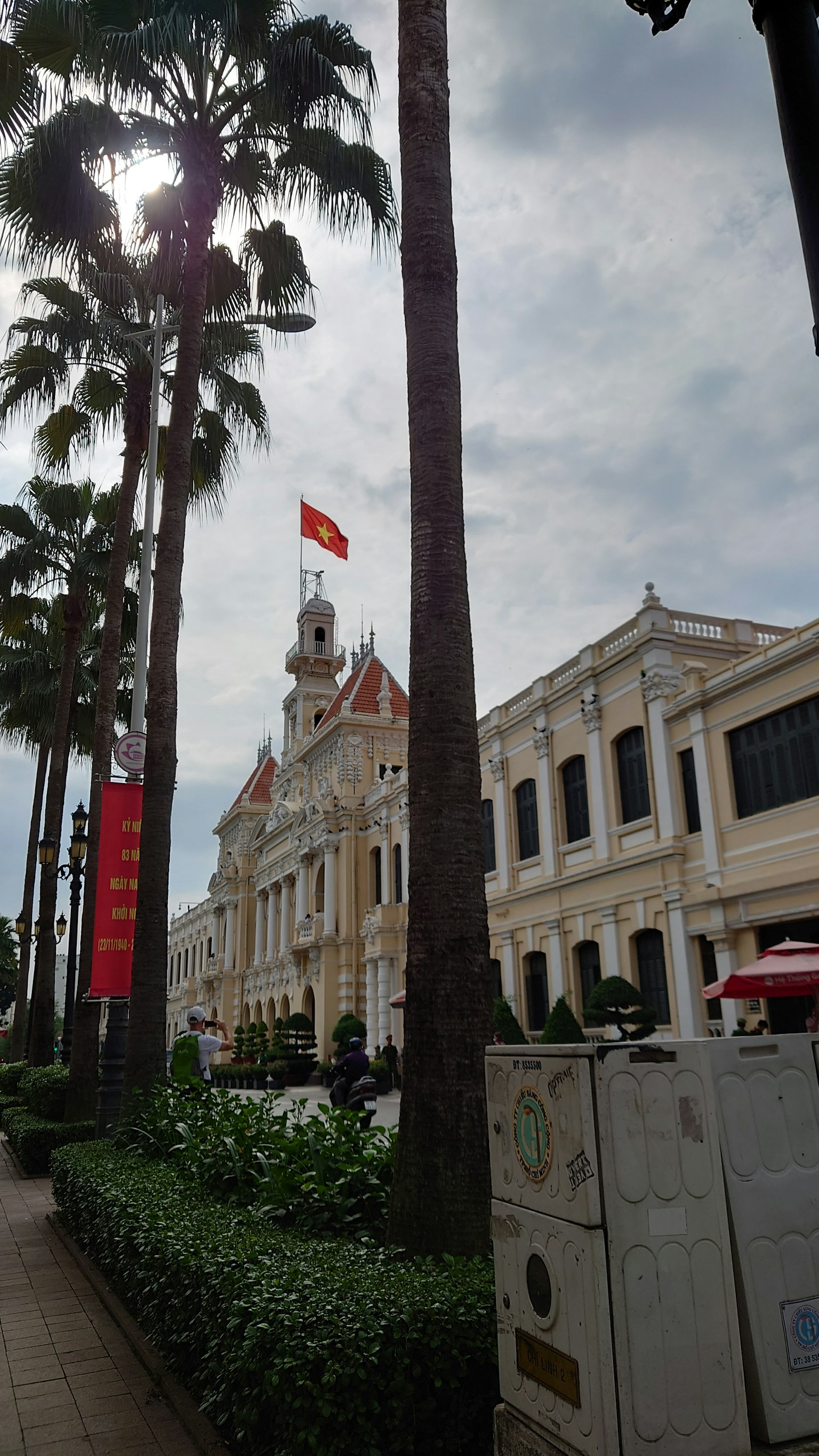 View of Ho Chi Minh City Hall with palm trees and cloudy sky