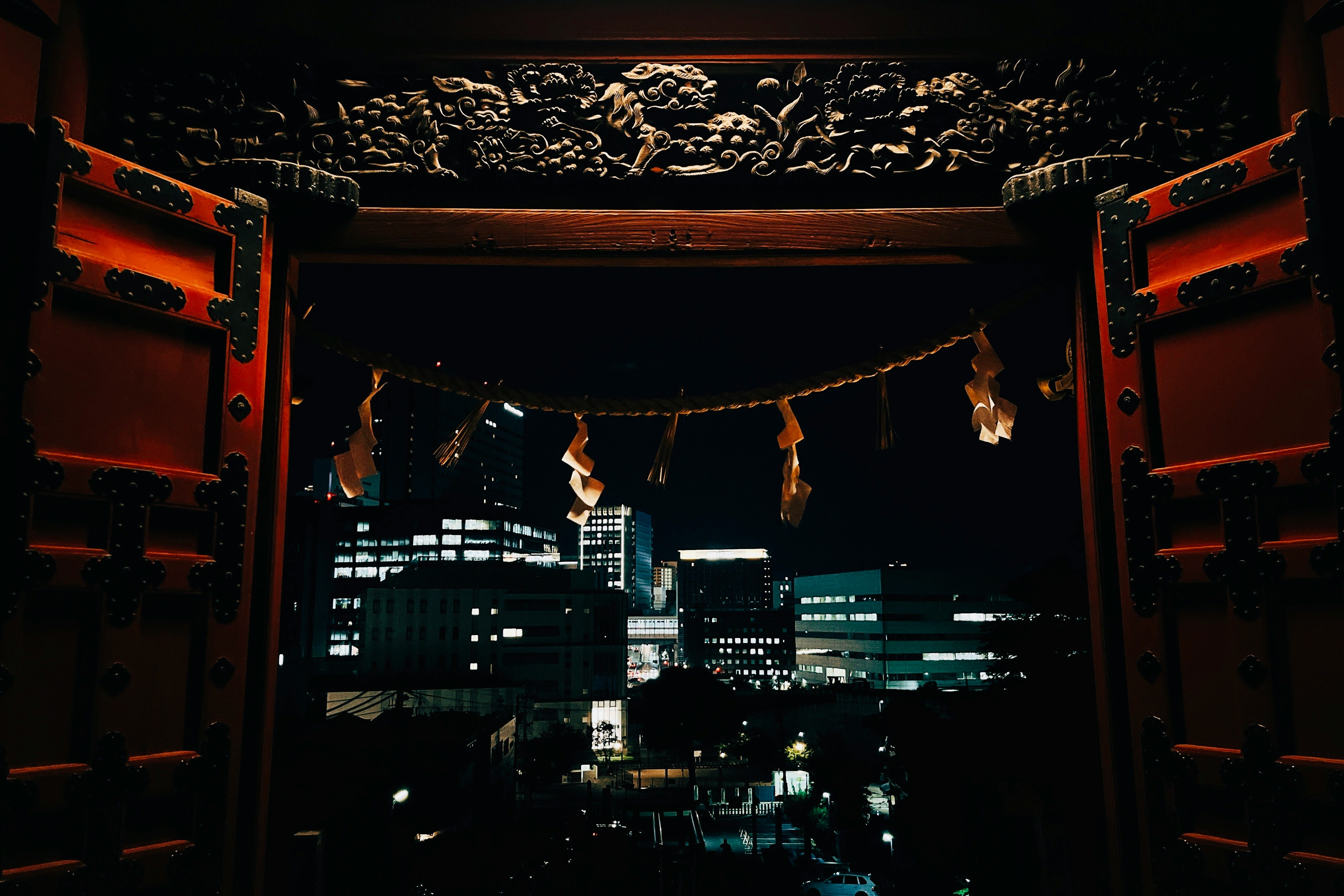 朱塗りの鳥居越しに広がる夜景の街並み