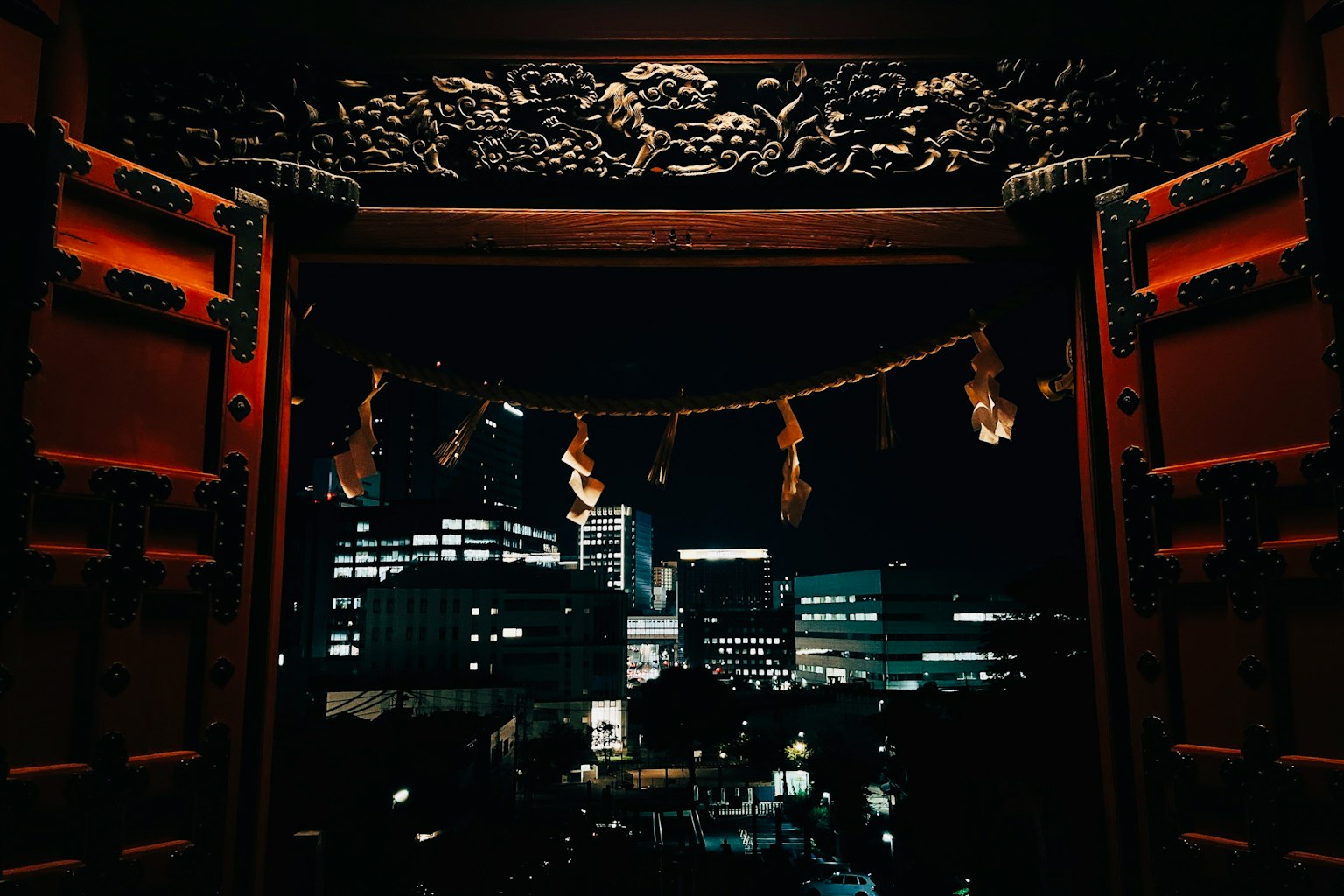 传统建筑的门框架着夜间城市景观，雕刻精美