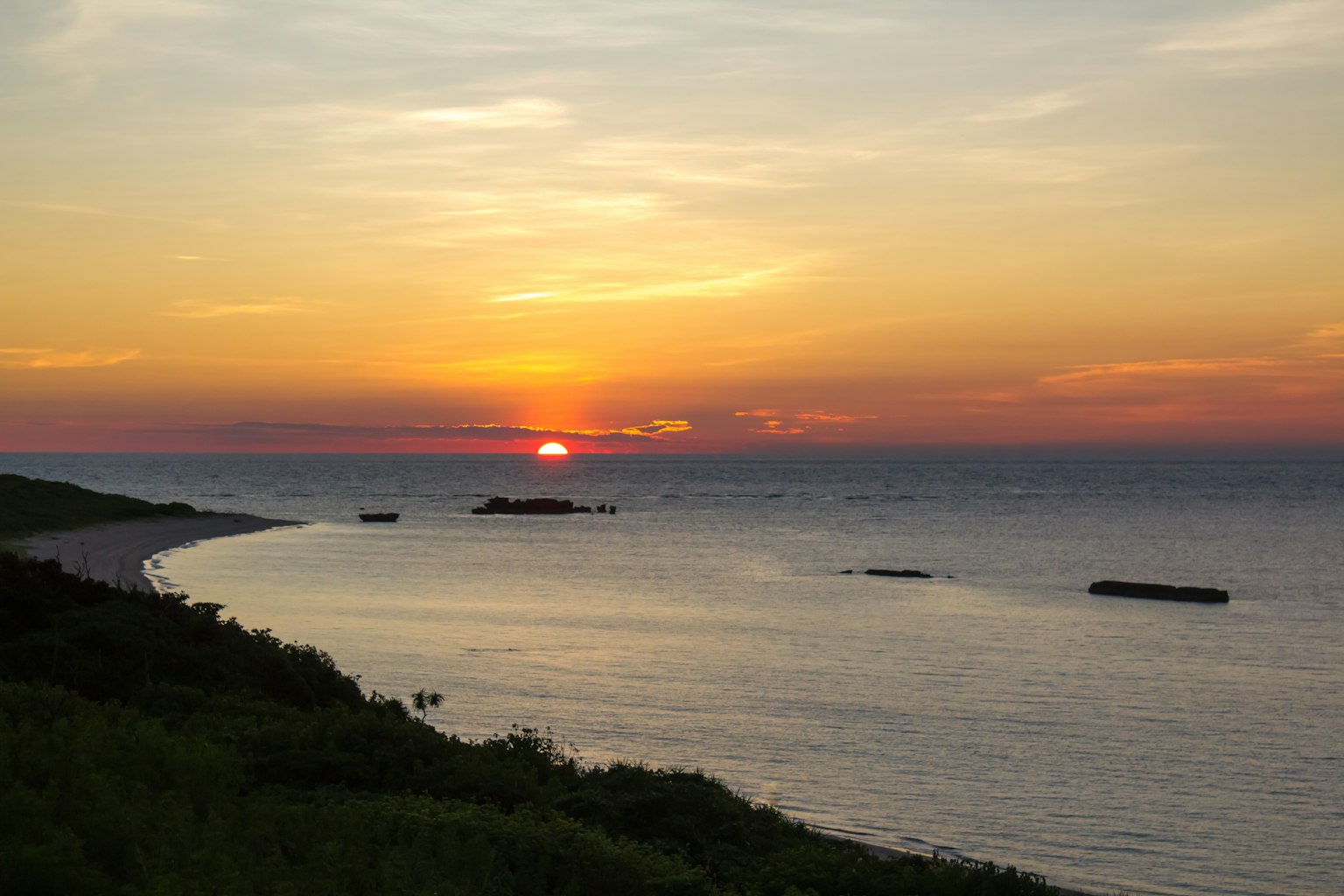 Bellissimo paesaggio di un tramonto sull'oceano con erba verde e onde calme