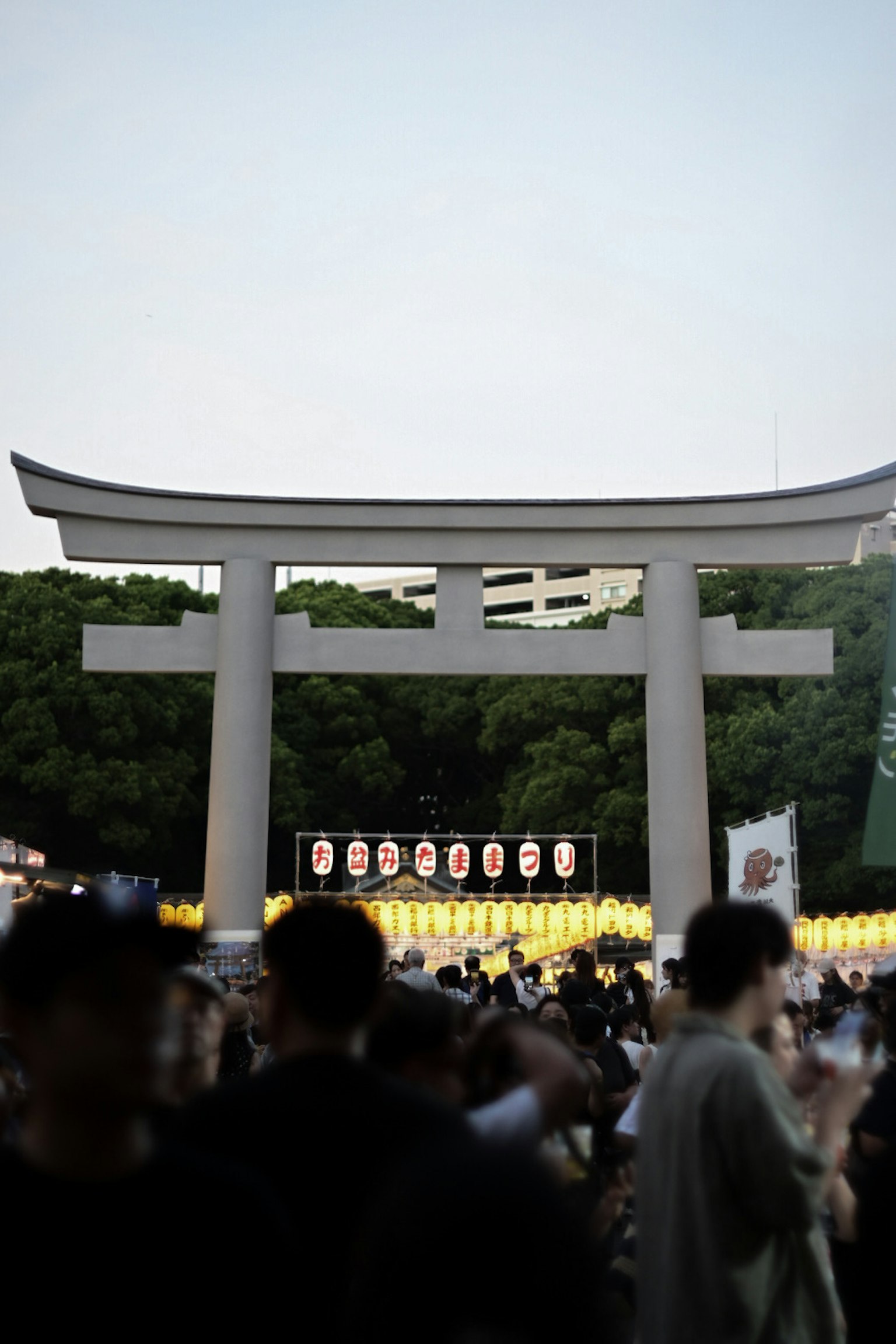 Foule rassemblée devant un torii lors d'un festival