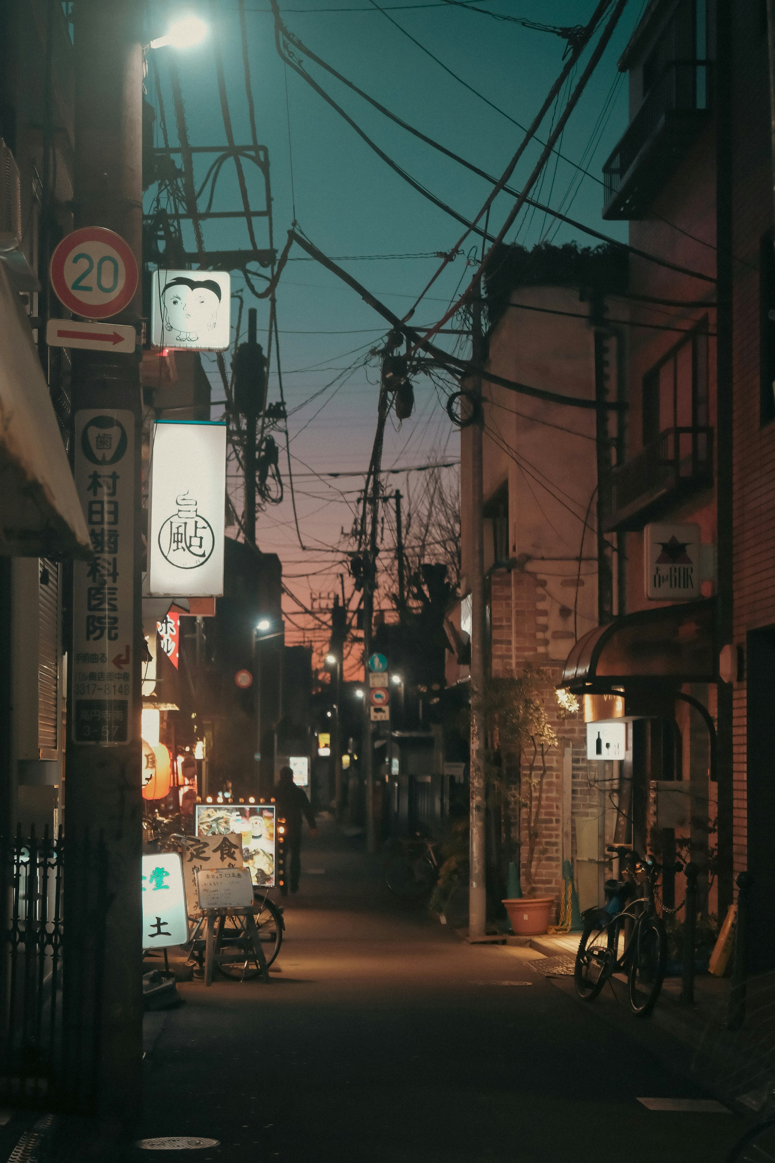 夕暮れの路地に並ぶ街灯と自転車のある商店街の軒先