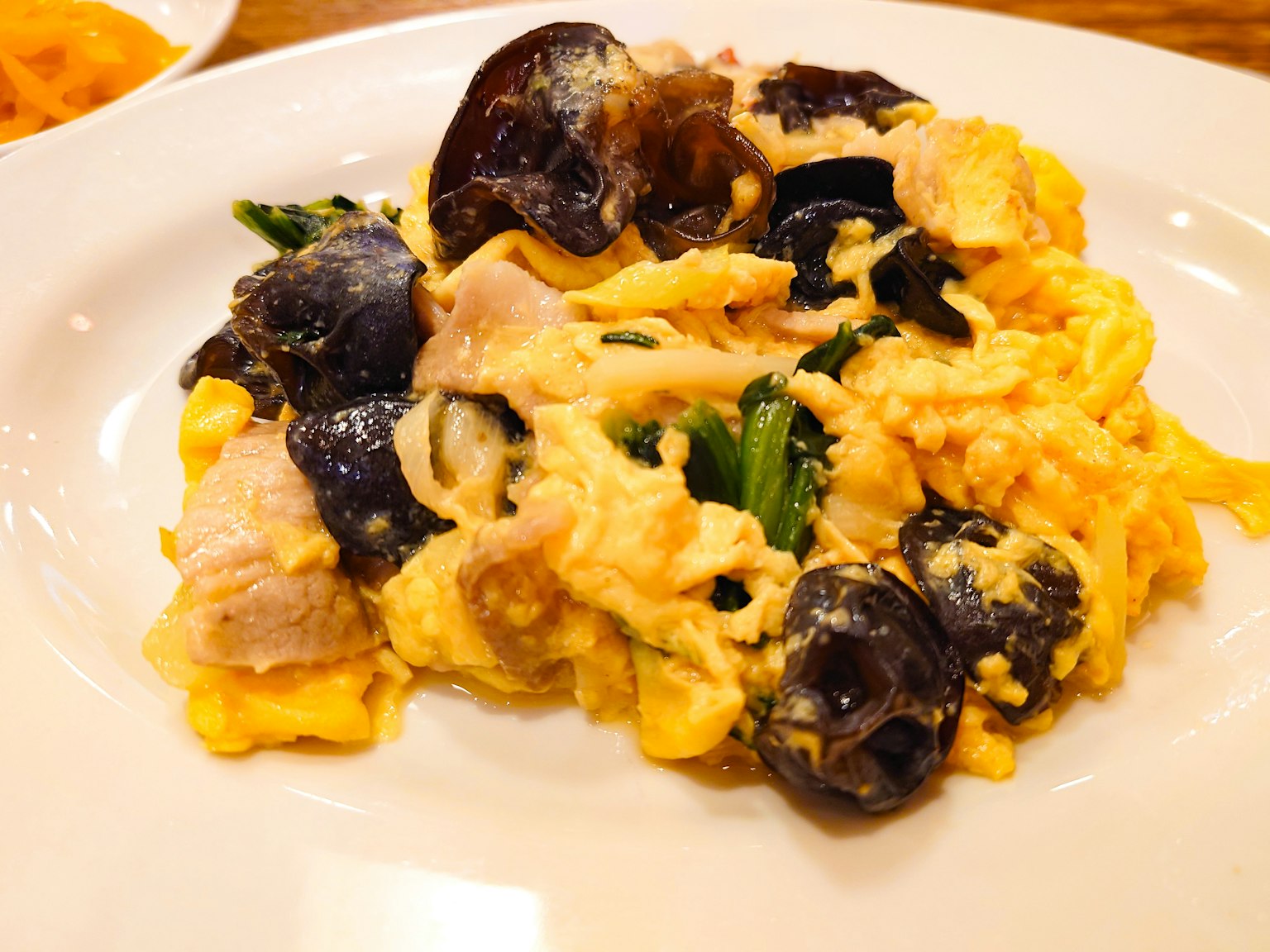 Piatto di uova strapazzate con molluschi neri e verdure verdi