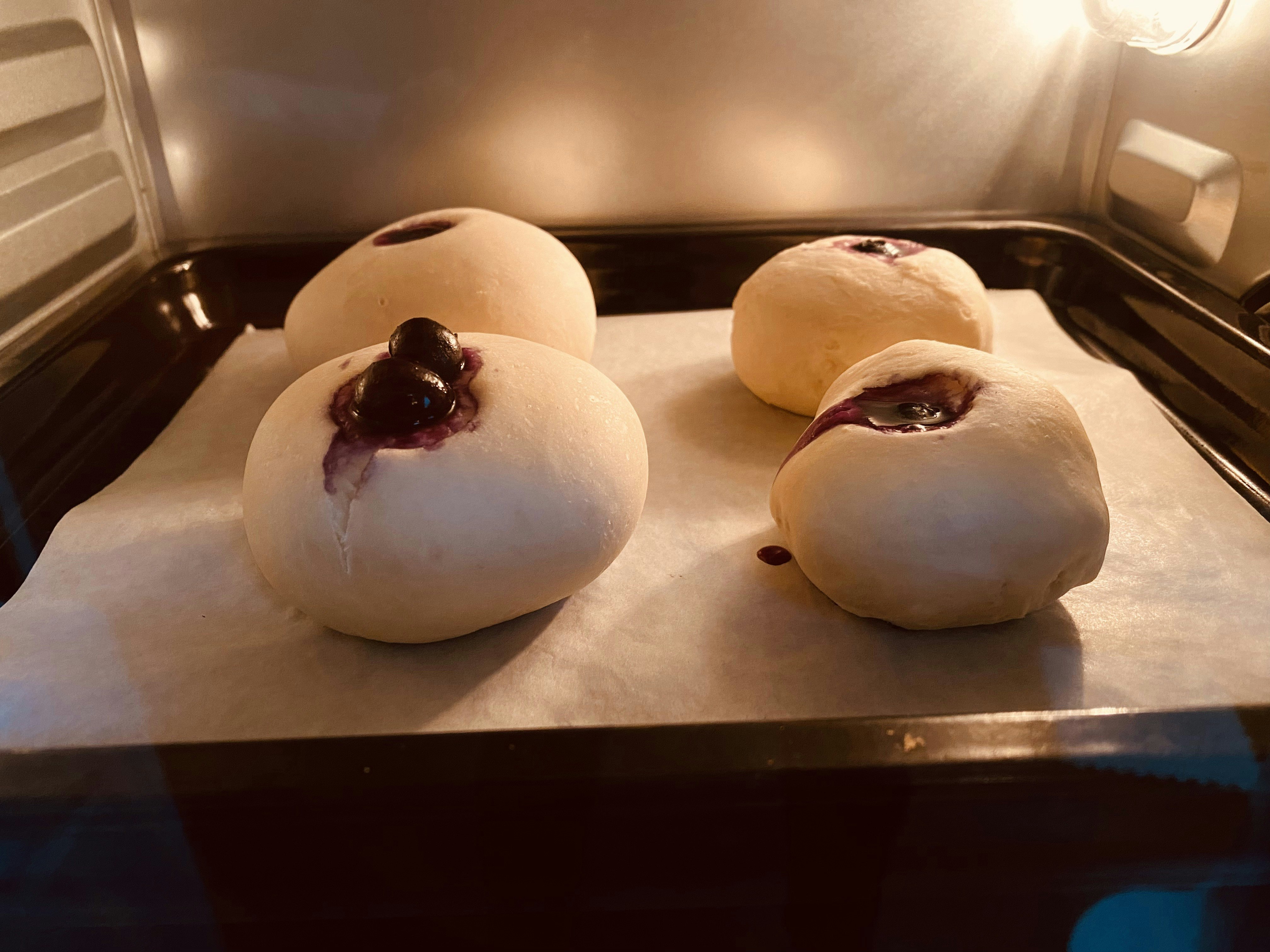 トレーに並ぶ丸いパンと焼き色のある具材のあるベーカリー商品画像