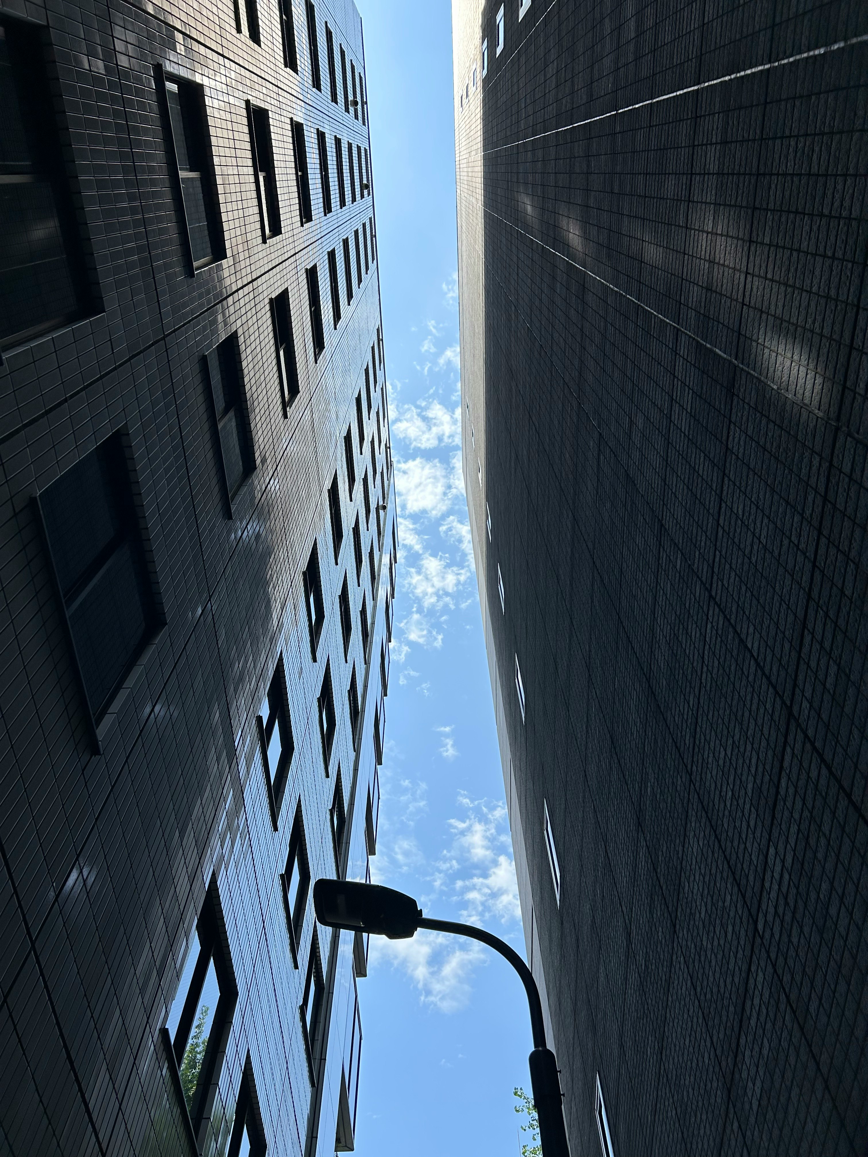 Narrow alley between buildings looking up at a clear sky with a streetlamp