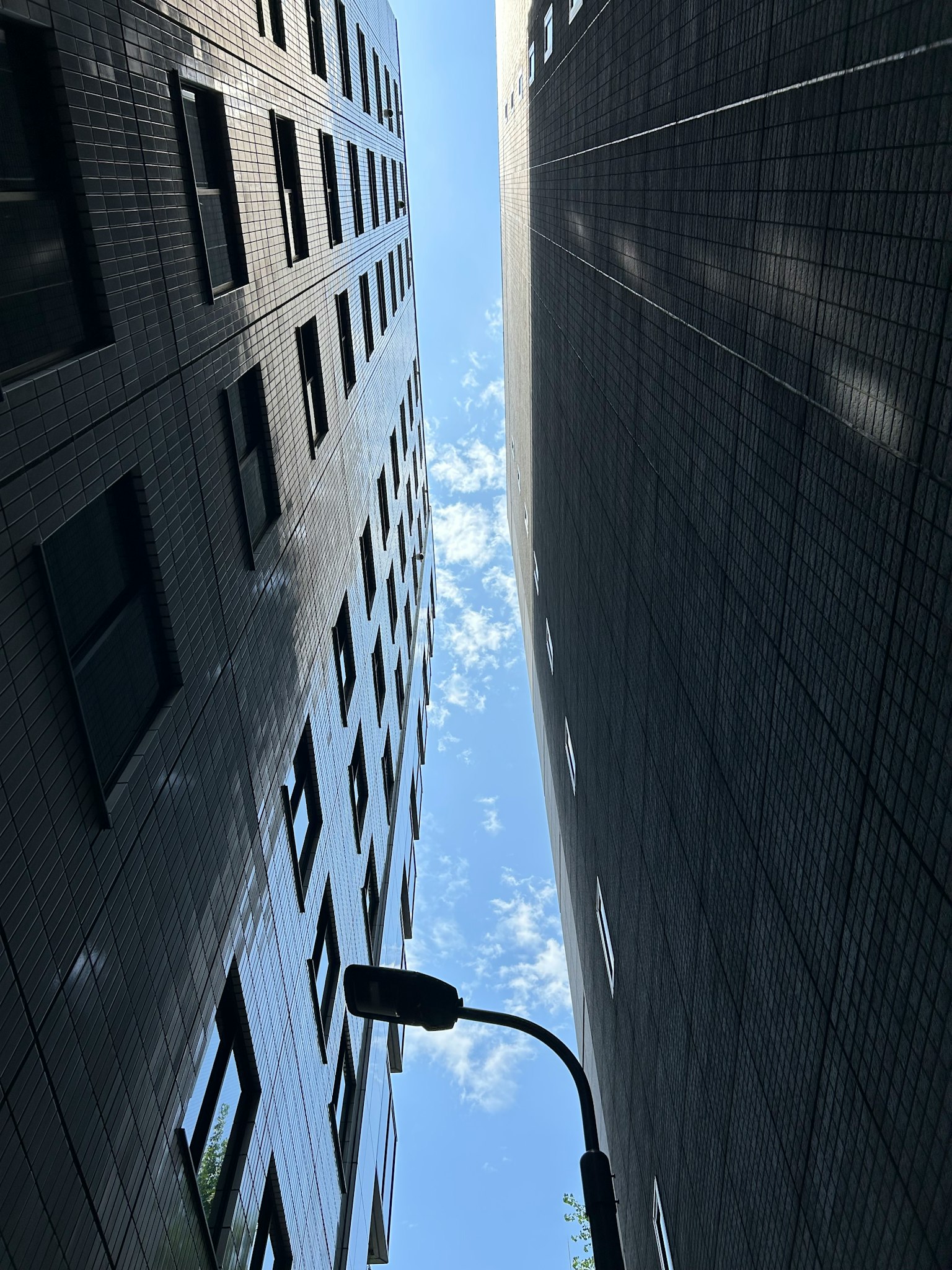 View of blue sky and clouds between tall buildings