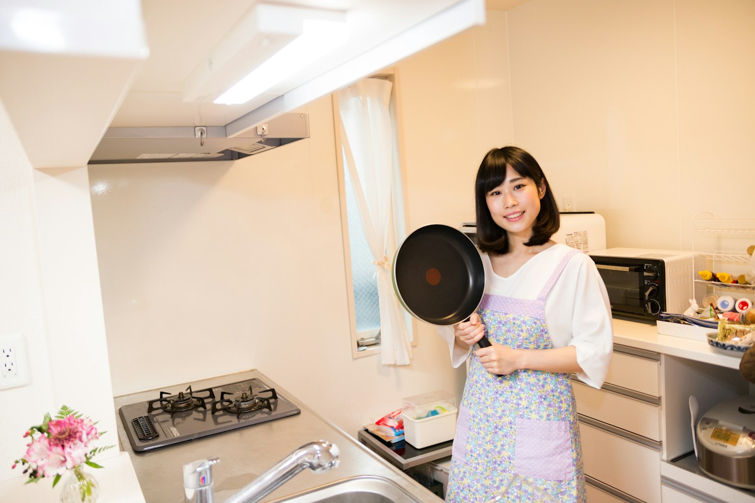 Una mujer sosteniendo una sartén en una cocina brillante