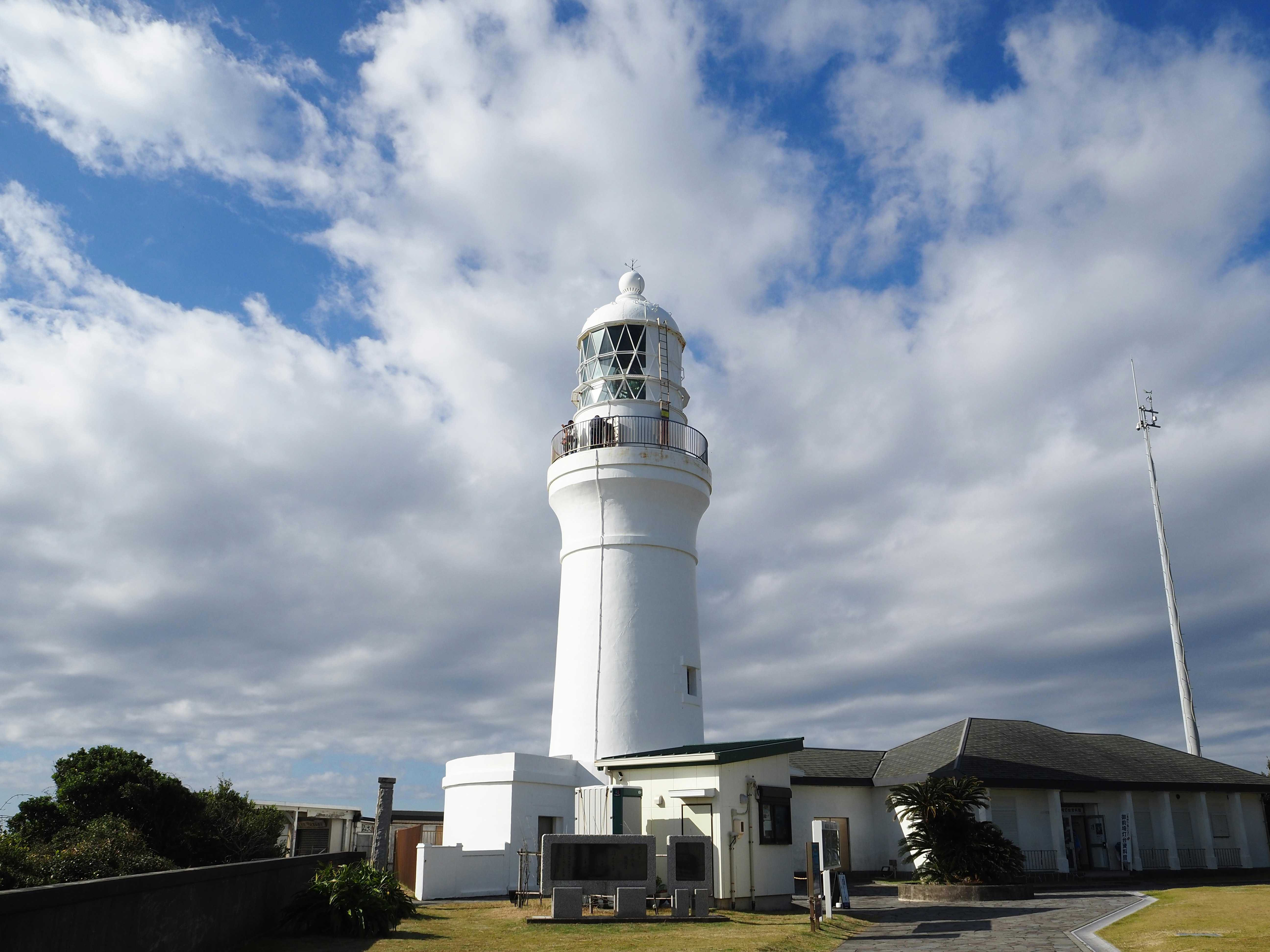 御前埼灯台の白い灯台と建物、青空の下の海辺の景観