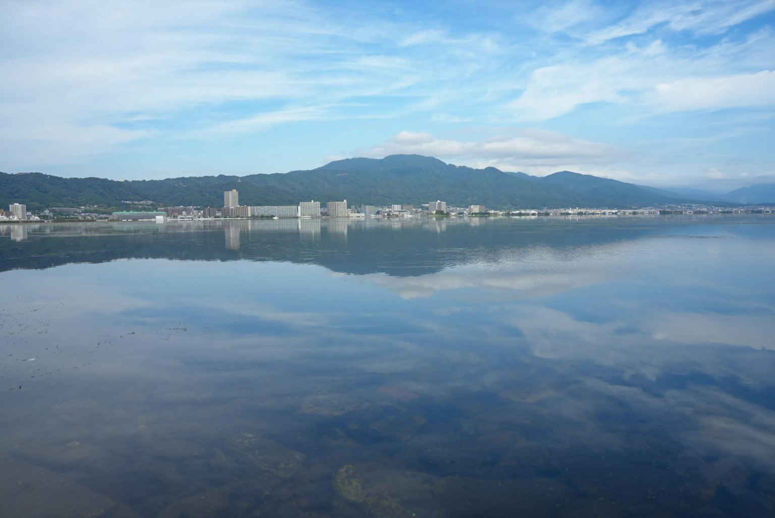 Vue pittoresque des montagnes et de la ville reflétées sur la surface calme du lac