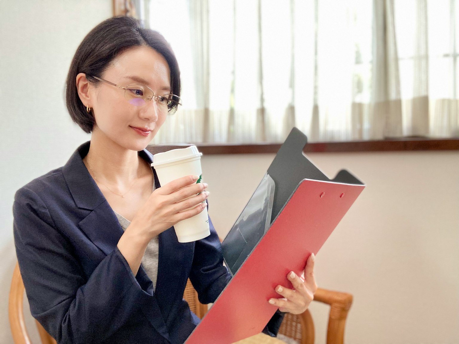 Femme en costume d'affaires tenant un café tout en regardant un dossier