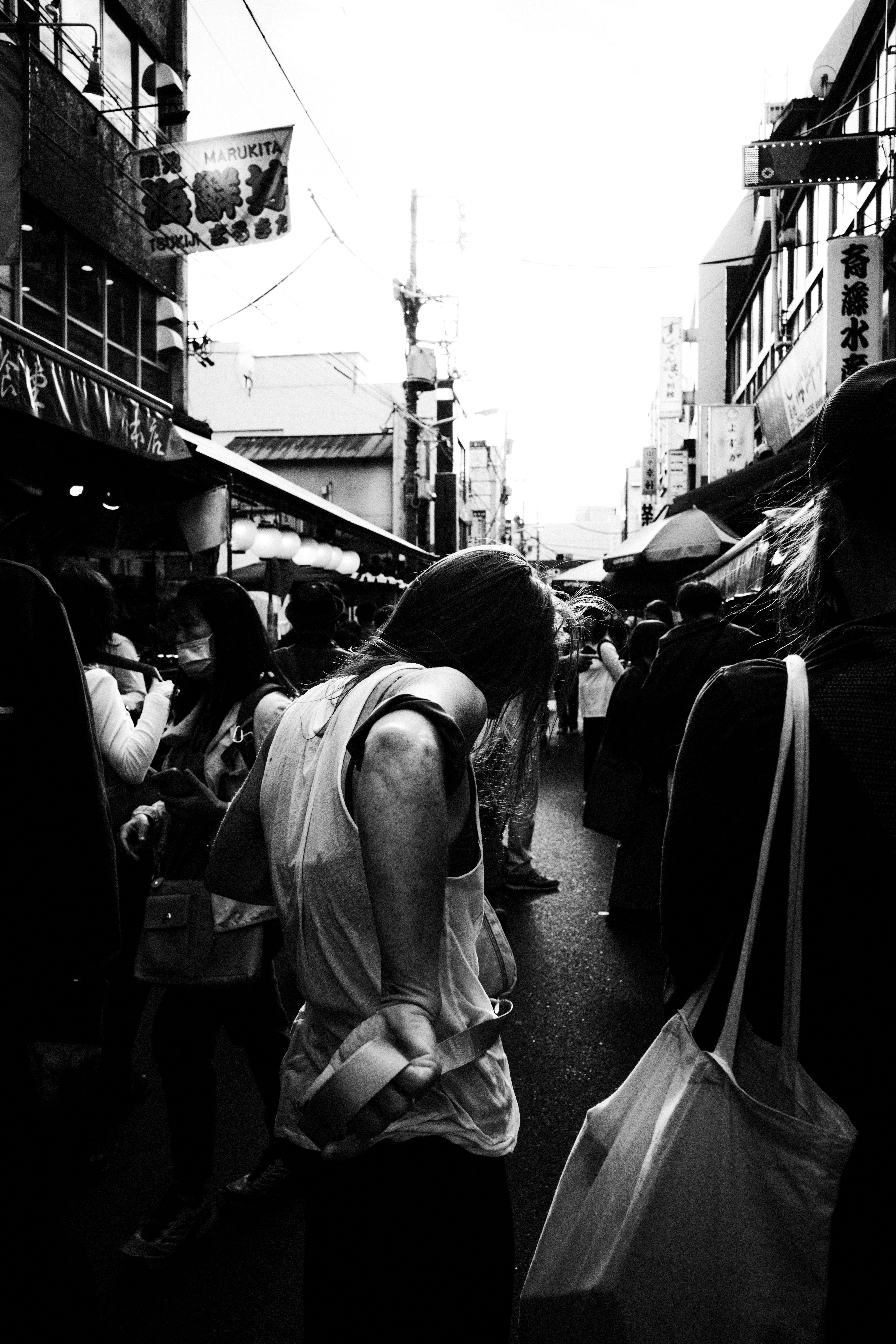 Back view of shoppers along a narrow alley lined with storefronts