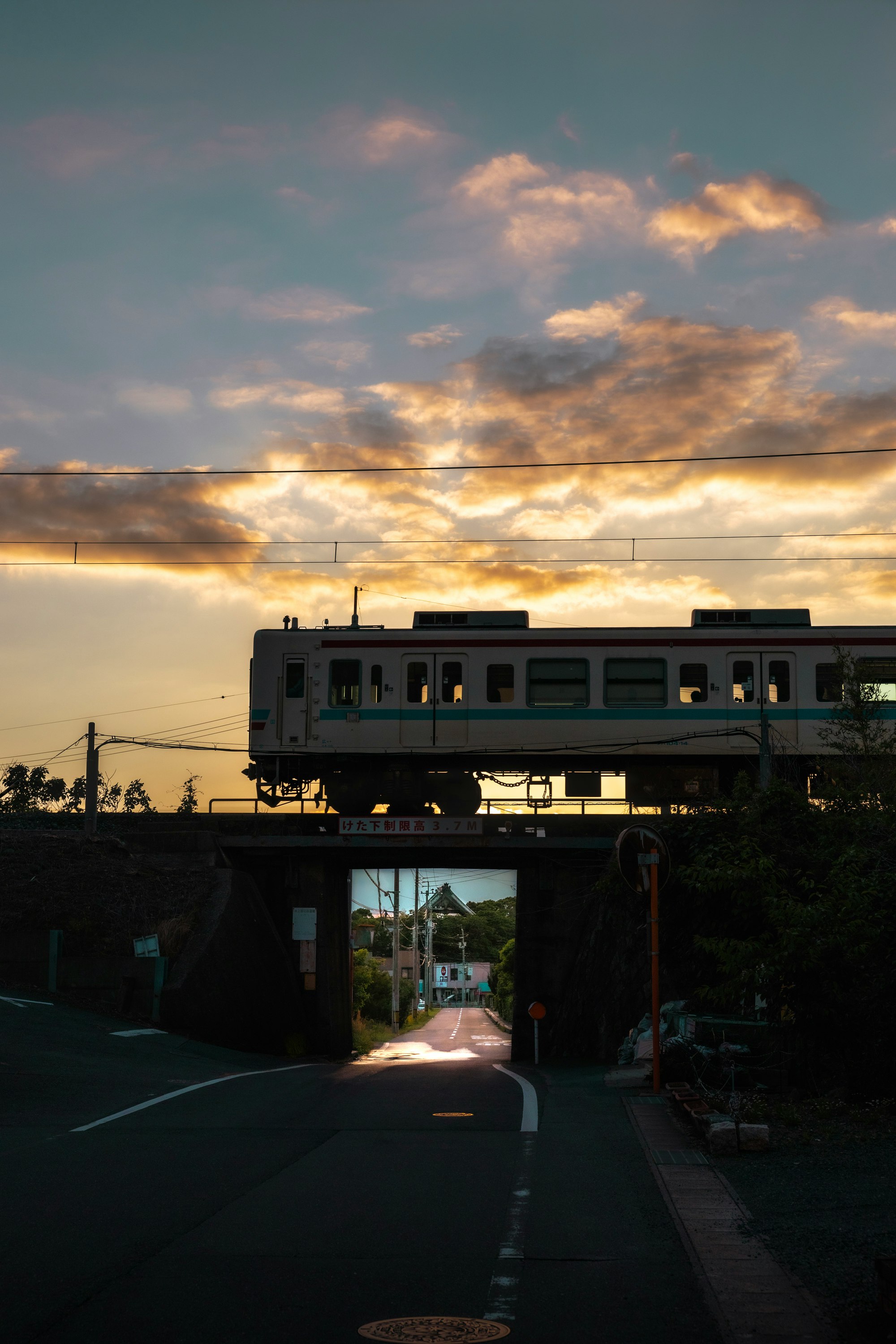 夕暮れの踏切を走る電車のある風景