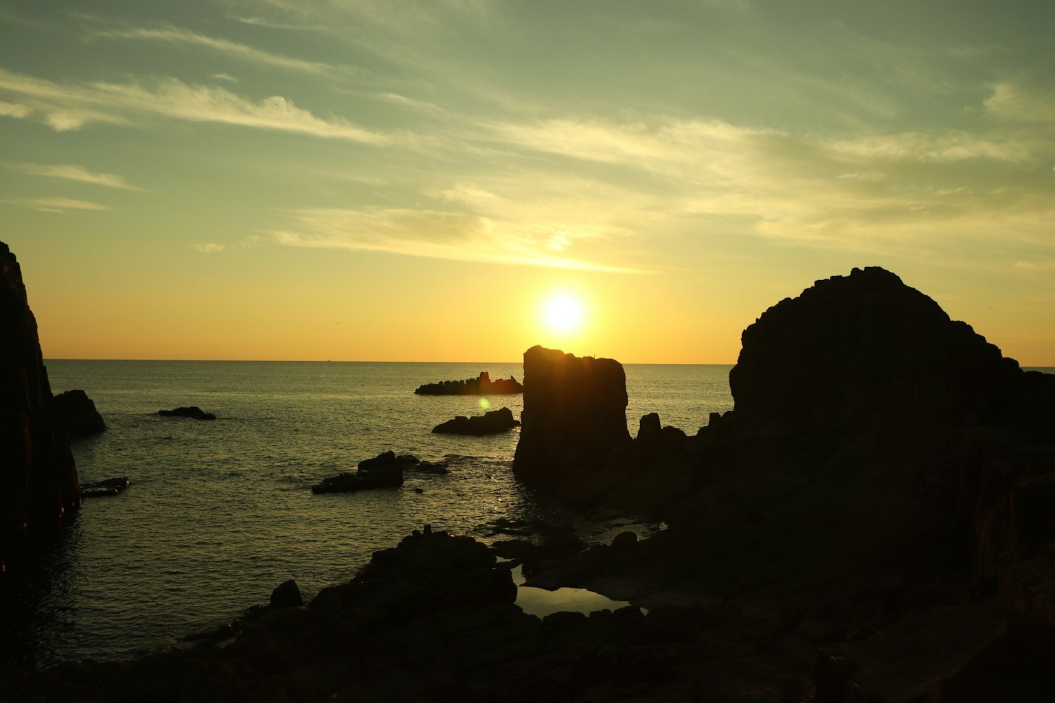 Coastal rocks silhouetted against a vibrant sunset