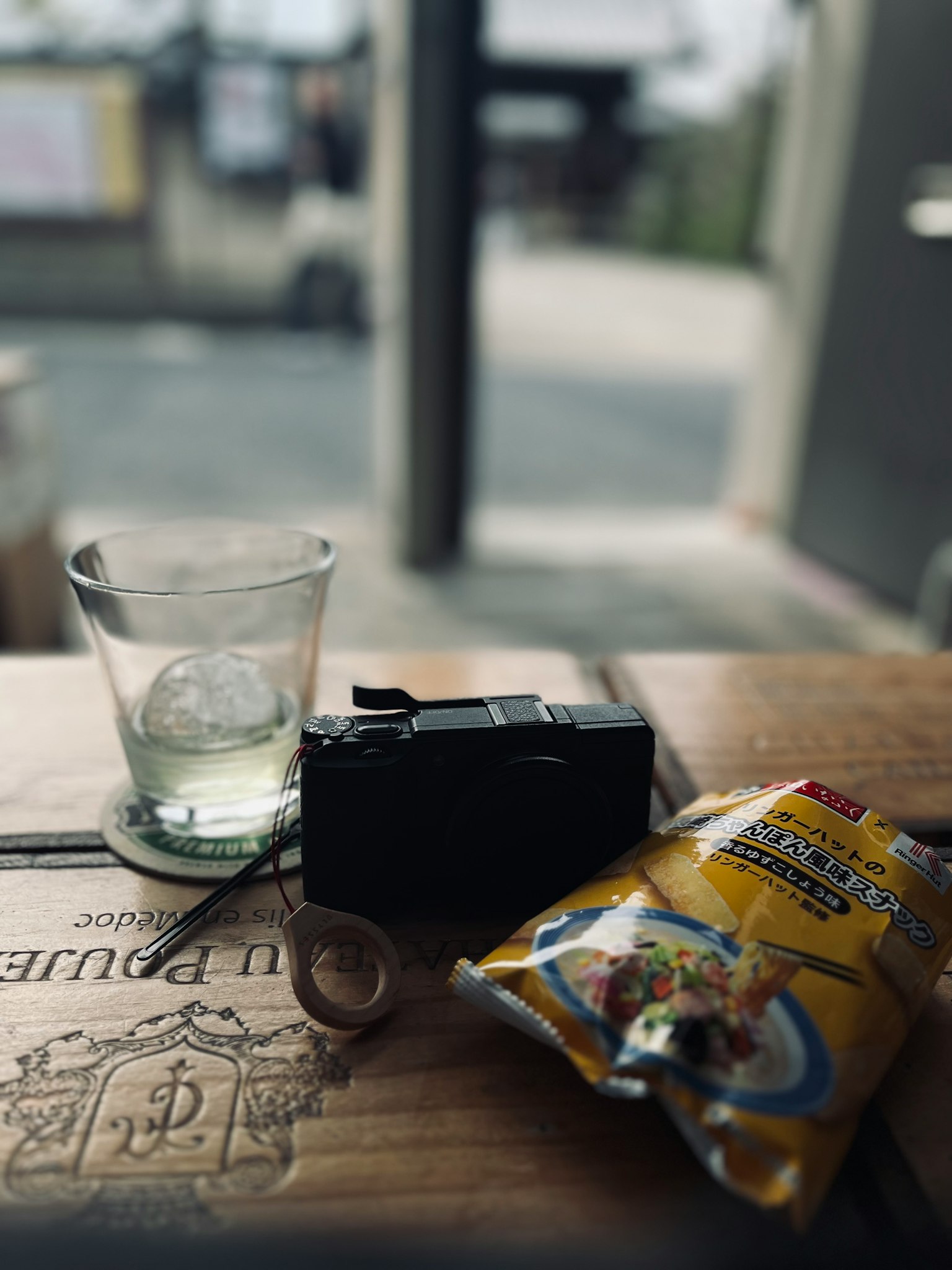 木桌上的相机、小吃和玻璃杯