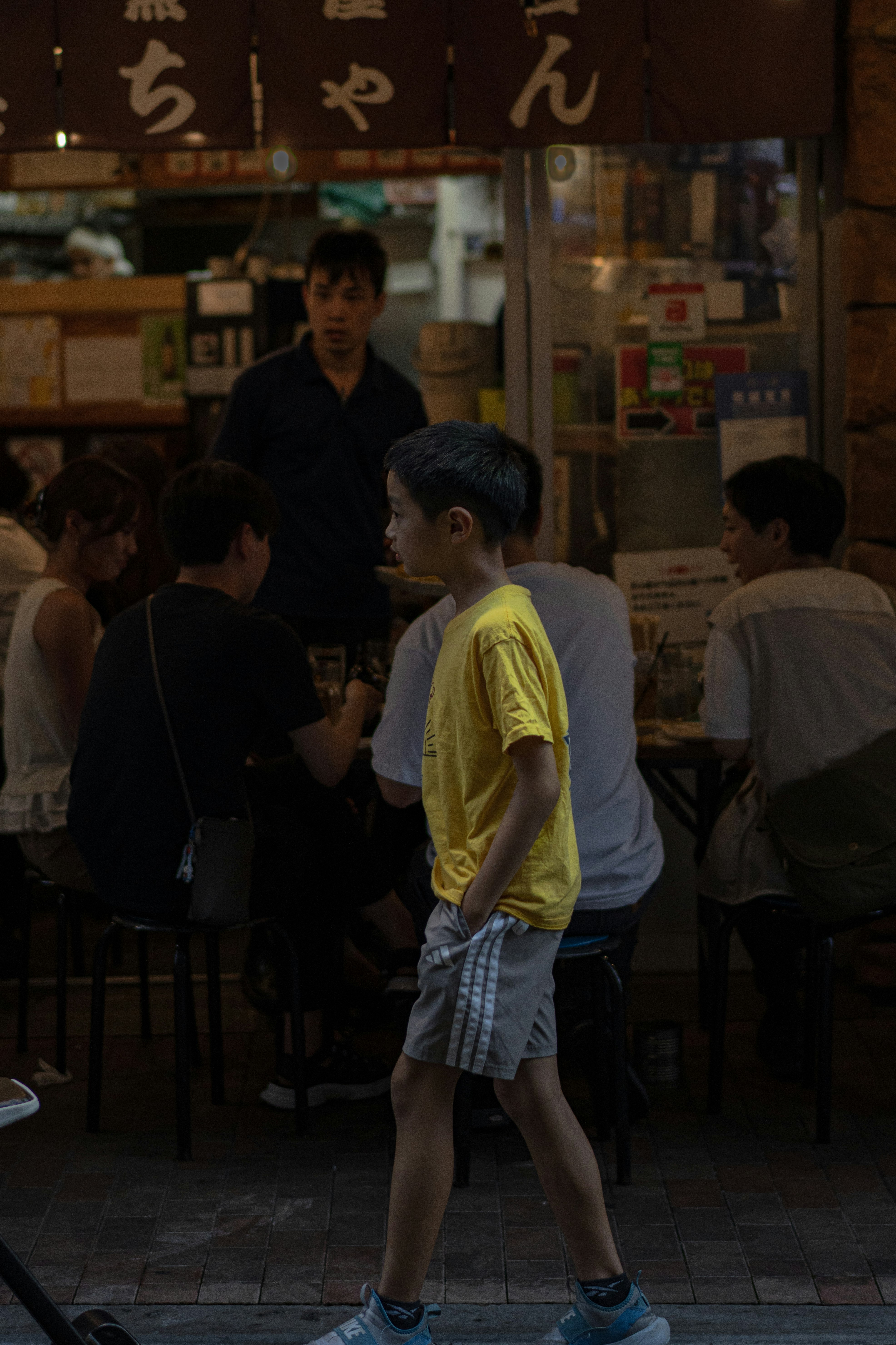 night street snap of adults passing by a food stall