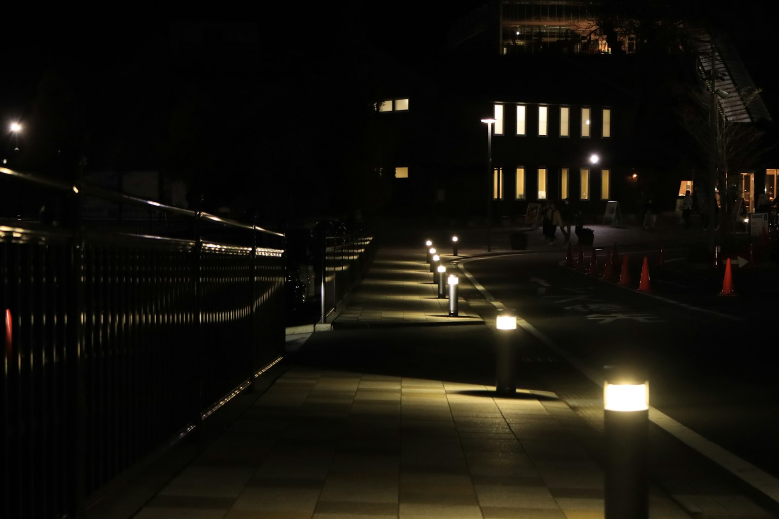 Sentiero illuminato da luci di notte con un edificio sullo sfondo