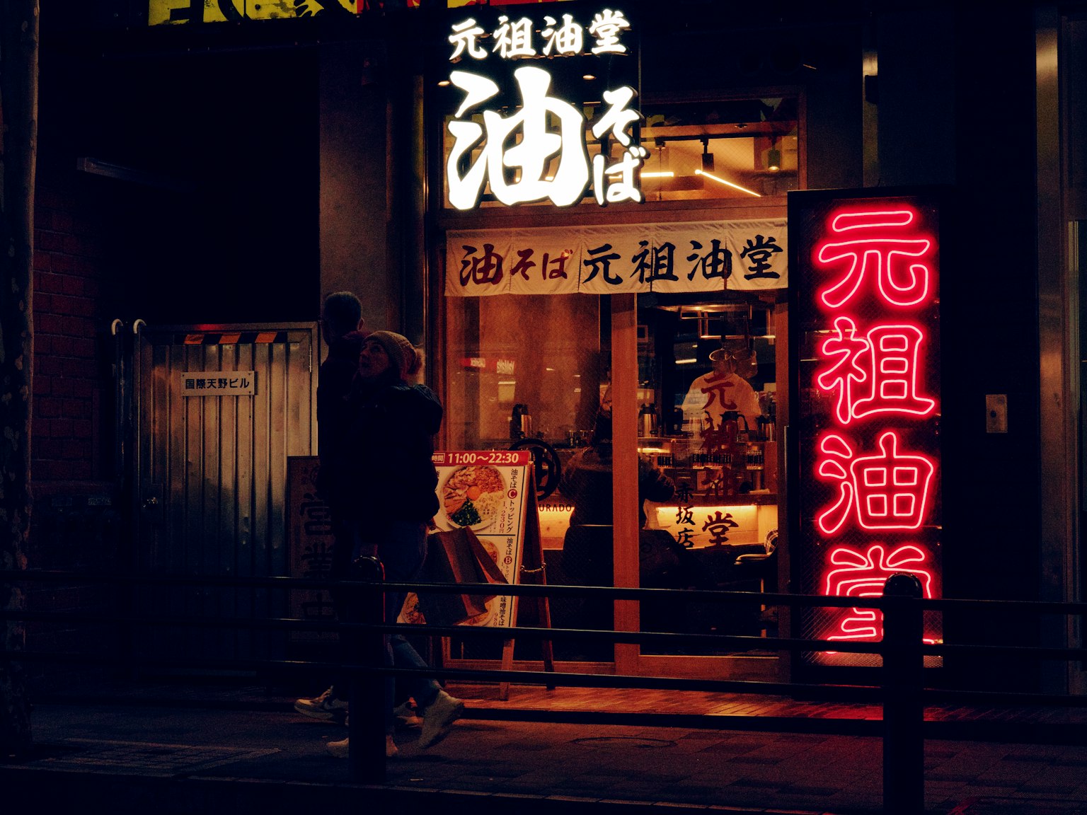 Exterior of Ganso Abura Soba restaurant at night with neon signs