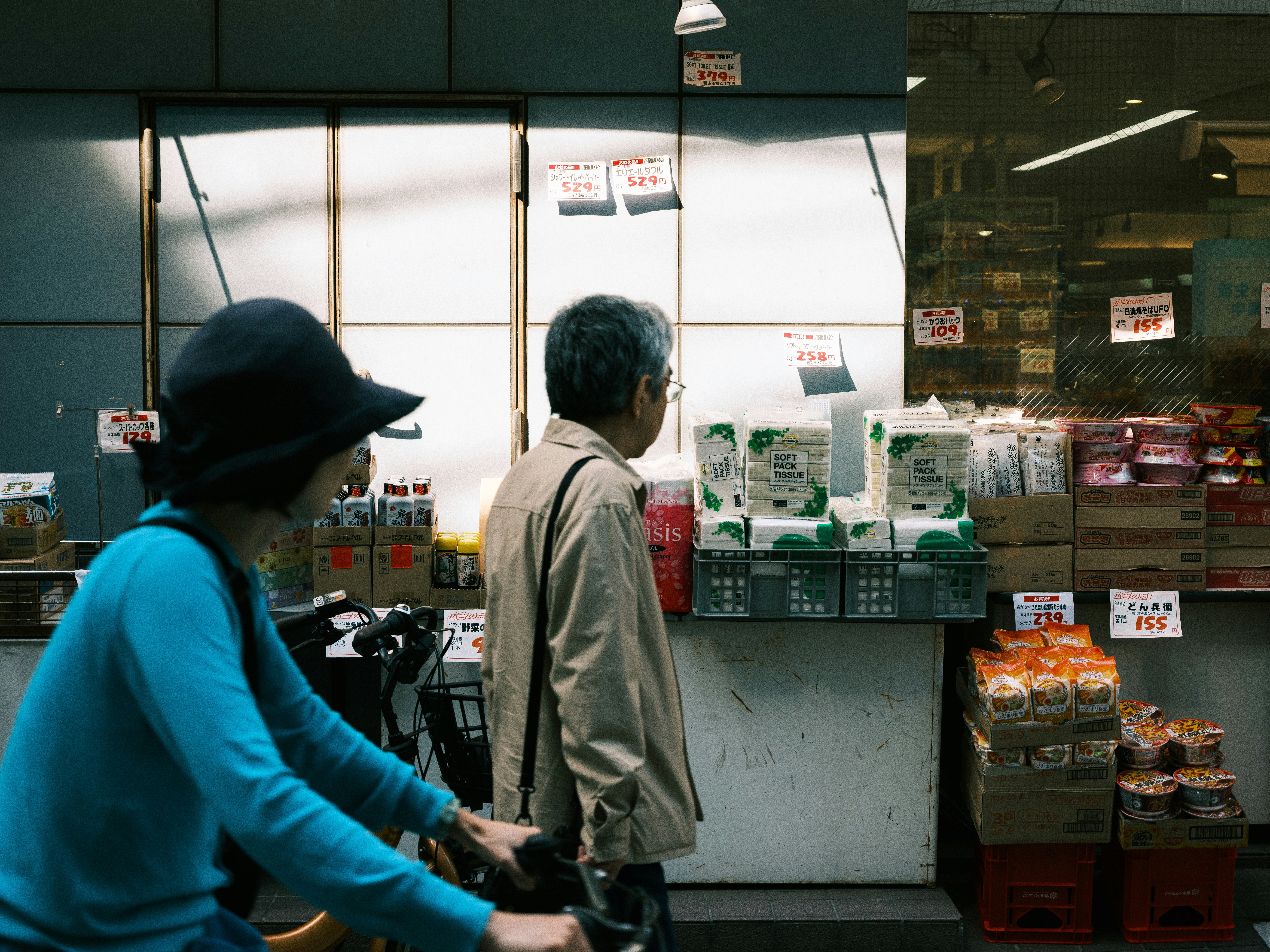店先の食品ケースと買い物客の後ろ姿