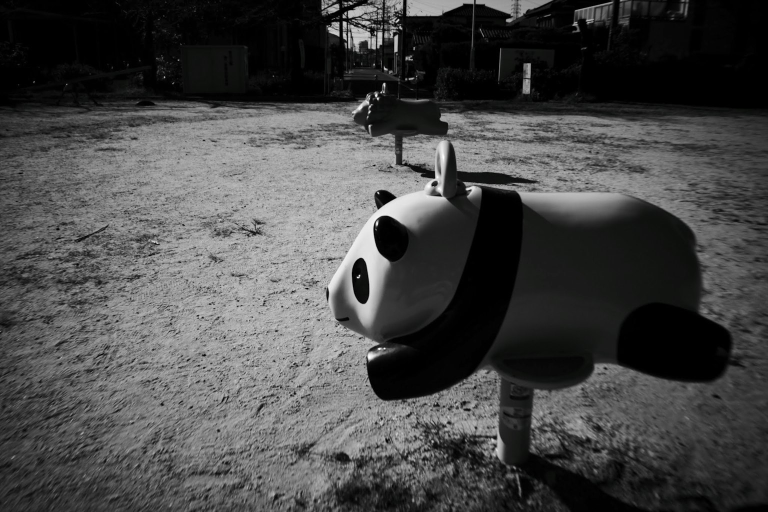 A panda playground equipment stands in a park with a black and white background