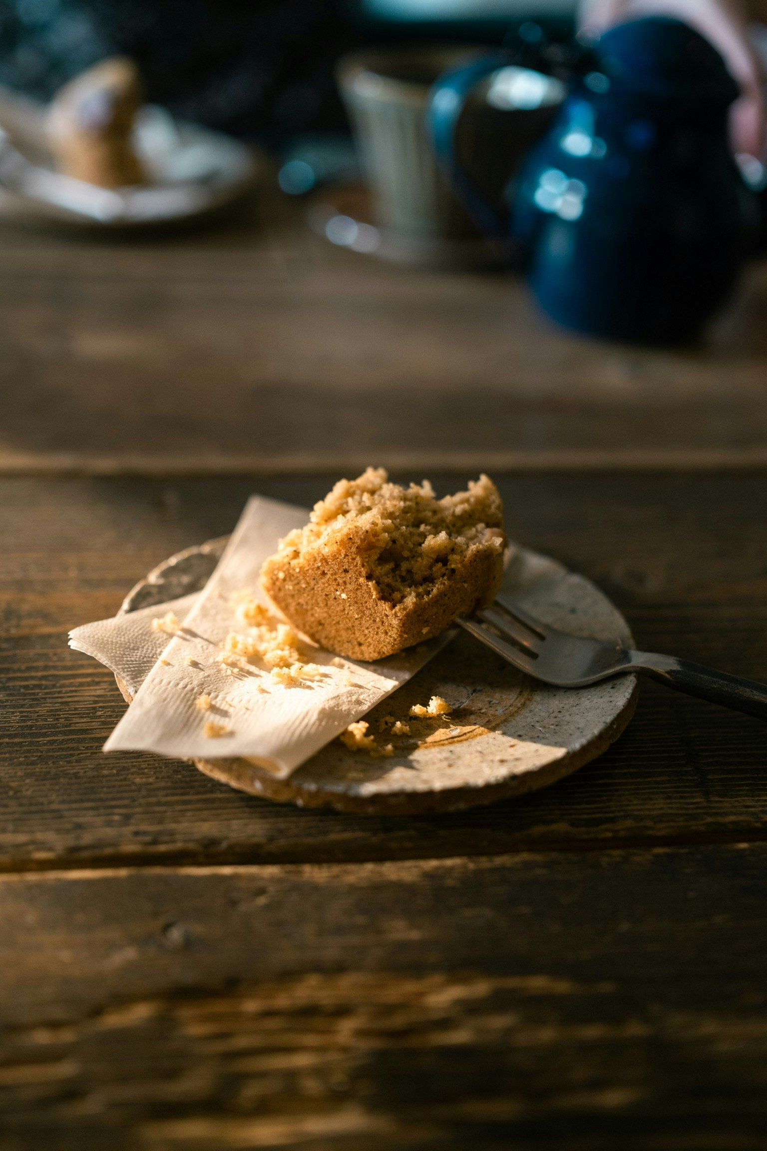 Sepotong kue di atas piring dengan garpu di atas meja kayu