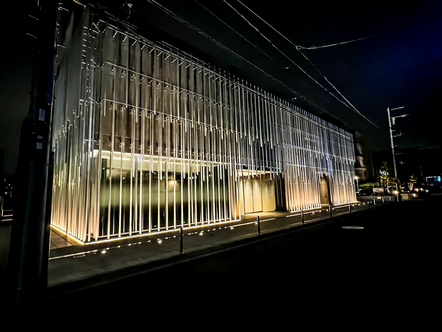 Edificio moderno in vetro illuminato di notte con illuminazione brillante e design a strisce