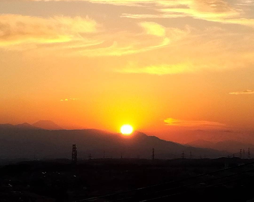 遠くの山並みを背景に沈む夕日