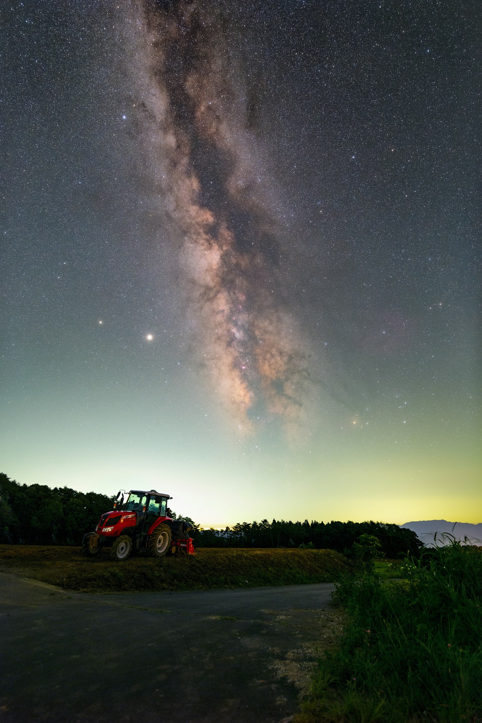 Tracteur rouge sous un ciel étoilé avec la Voie lactée