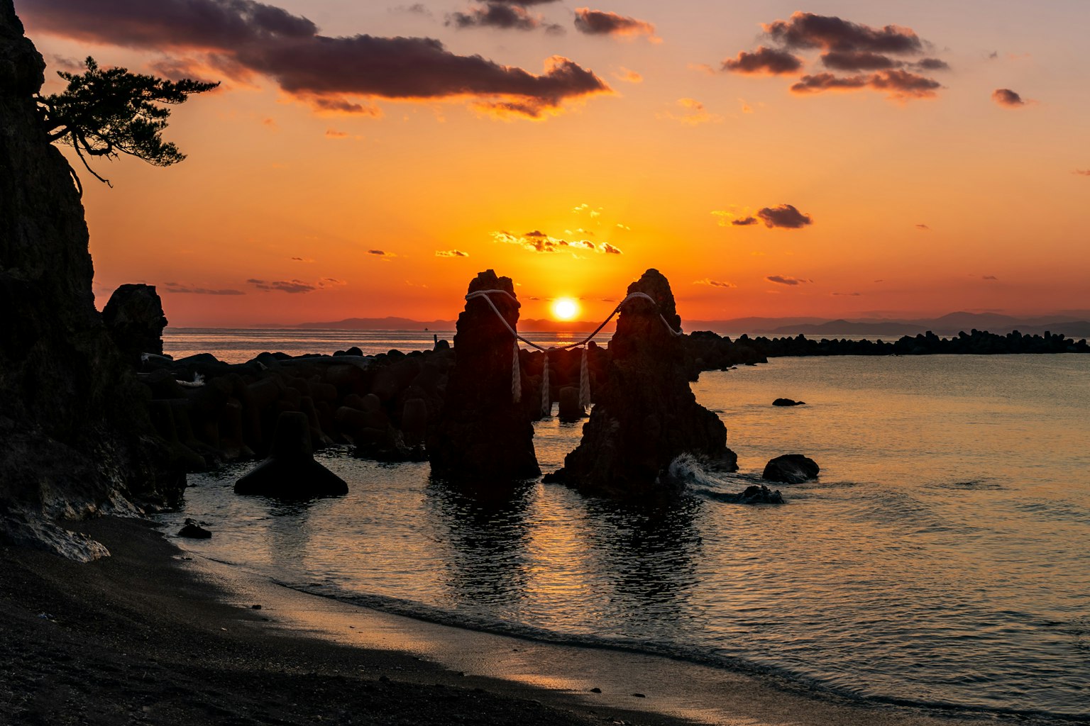 Tramonto sull'oceano con rocce in primo piano