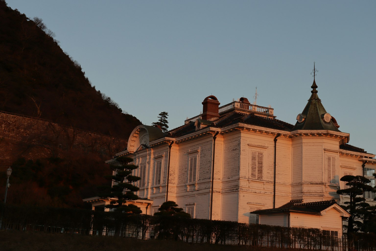 Mansión histórica blanca al atardecer con fondo montañoso