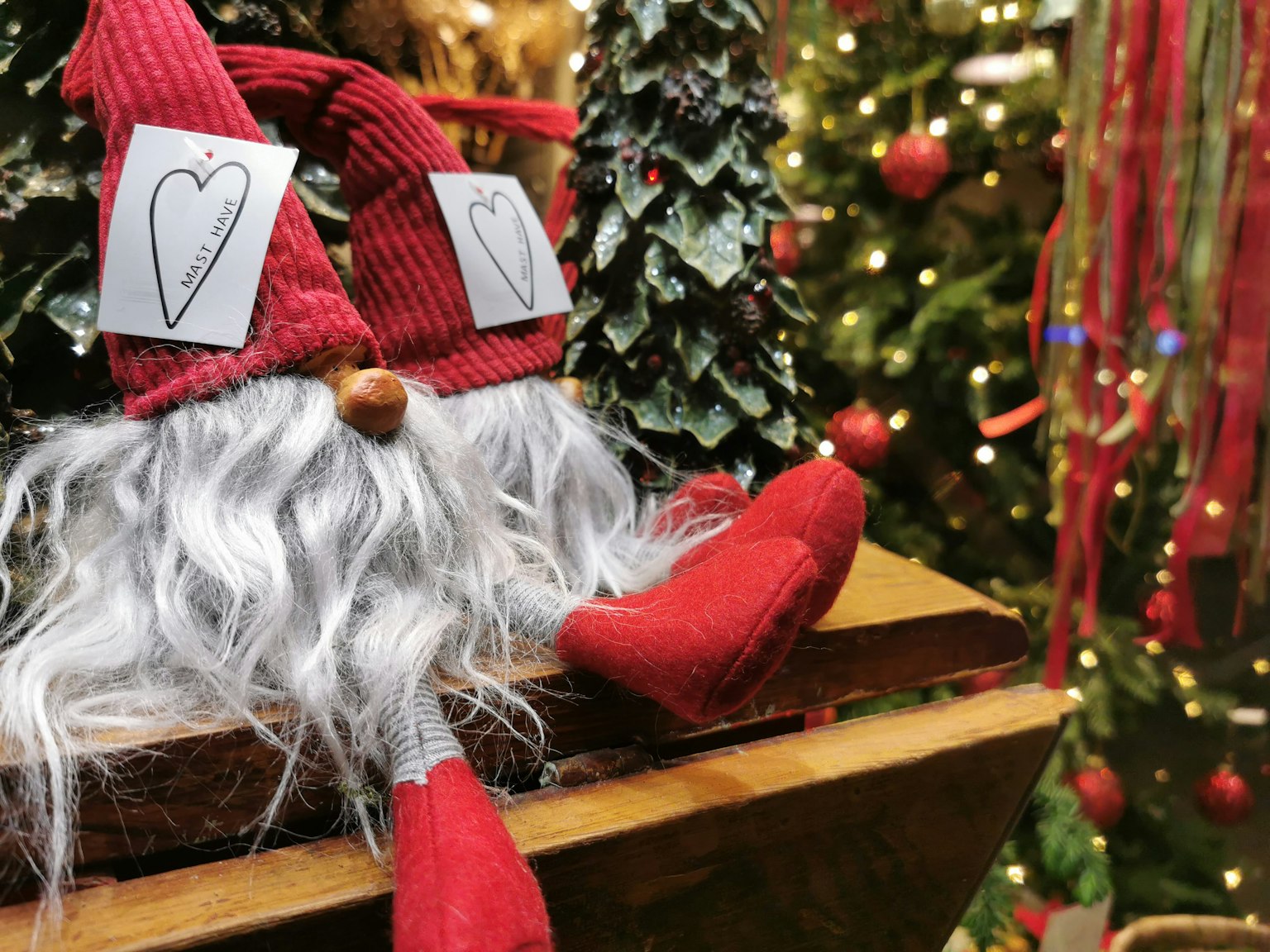 Una figura di Babbo Natale con un cappello rosso seduta davanti a un albero di Natale
