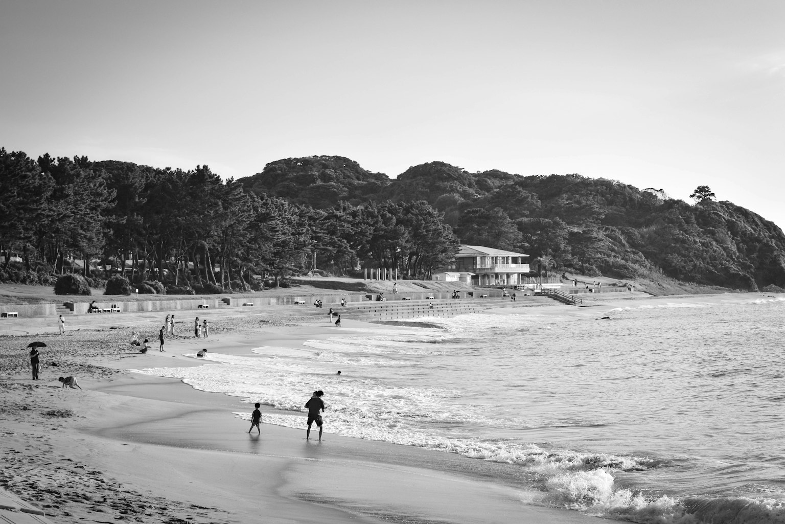 ผู้คนเล่นที่ชายหาดพร้อมคลื่นและทิวทัศน์ชายฝั่ง