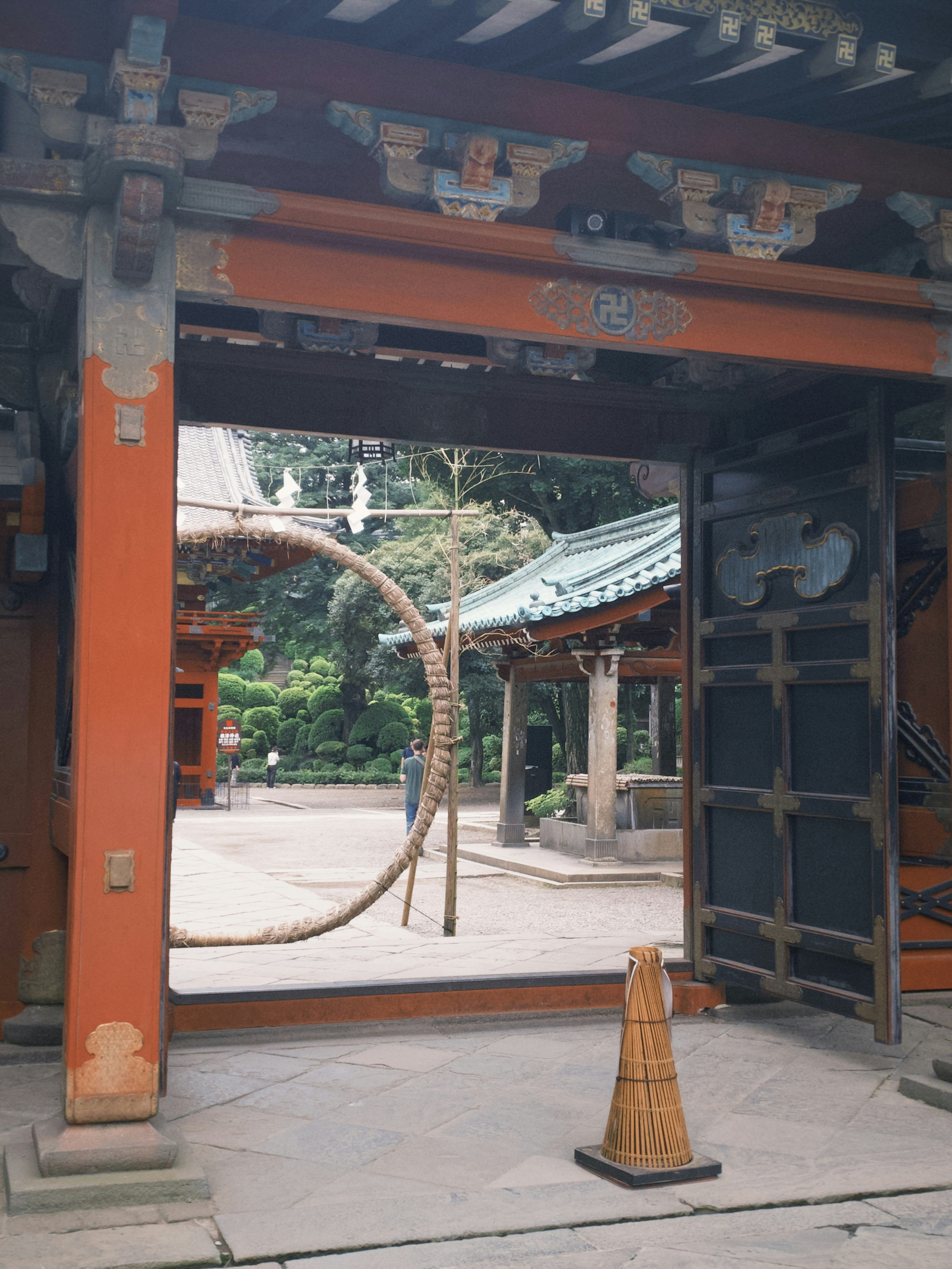 朱红色牌楼与石铺通道，庭院树木映入神社内院