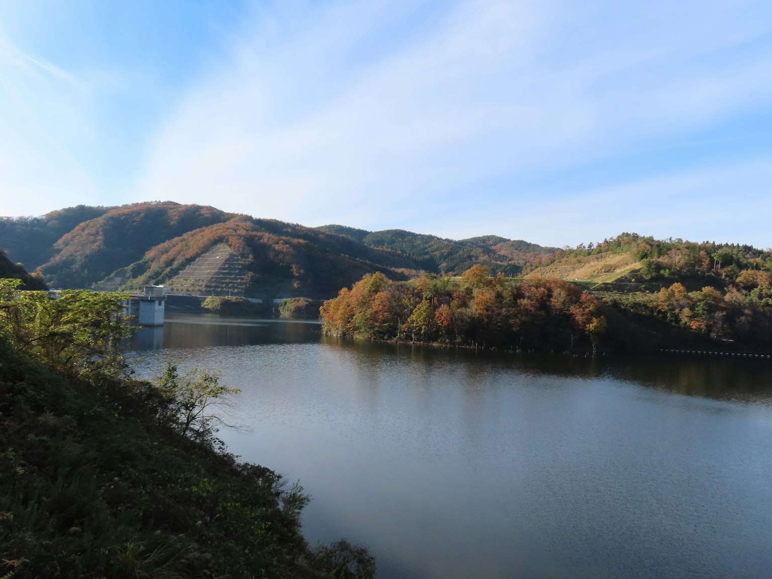 Vista panoramica di un lago circondato da foglie autunnali e montagne