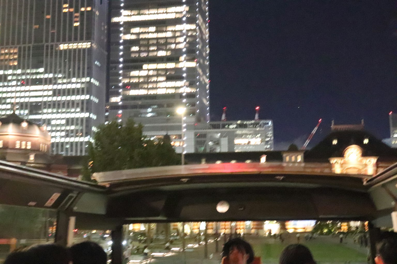 Vista nocturna de los rascacielos de Tokio con pasajeros en un autobús descapotable