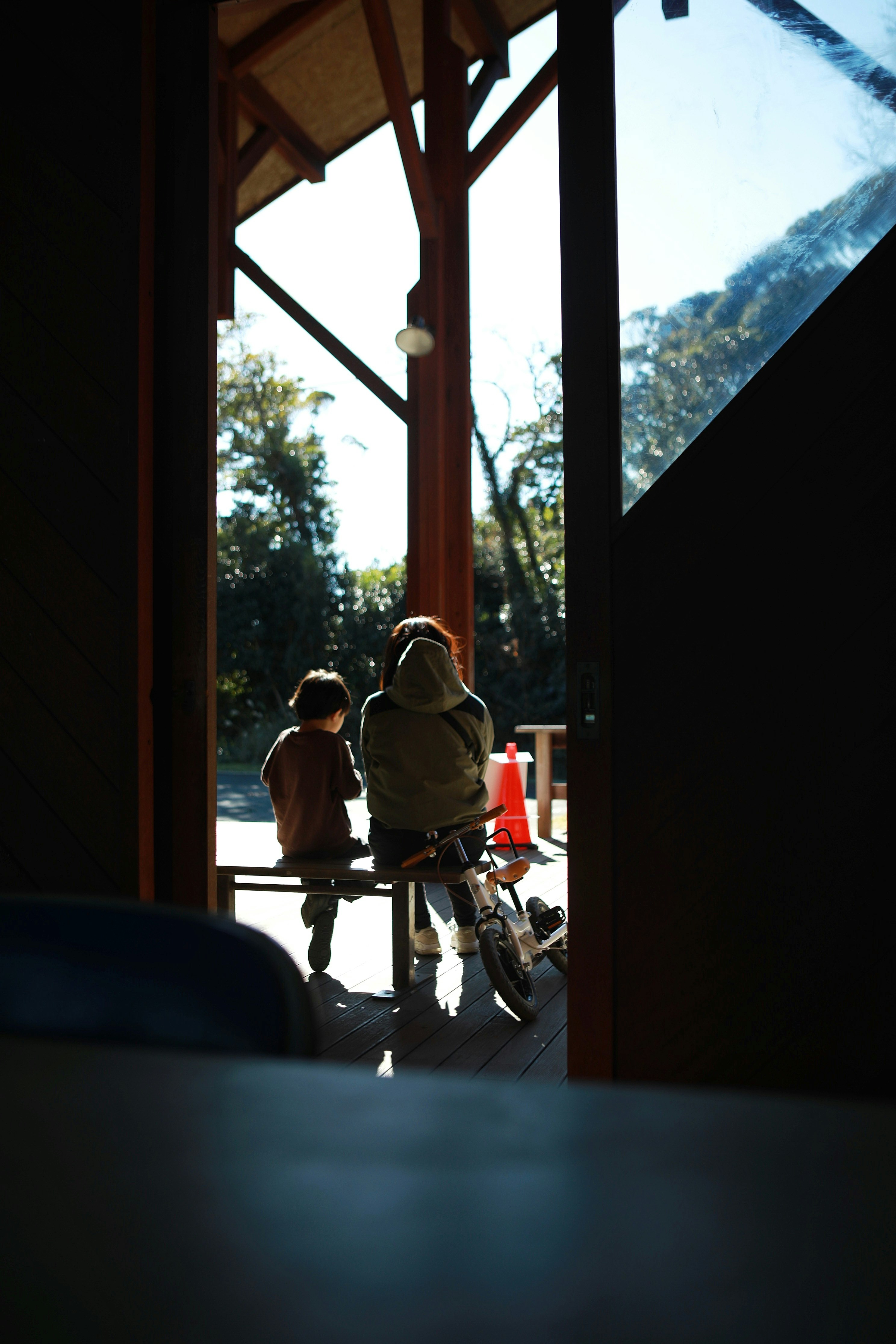 木の柱のある室内から見える自転車と子どもの遊び